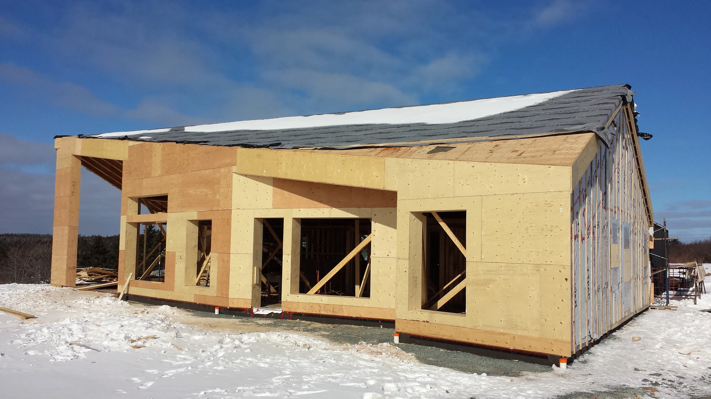 Deep Charcoal Interlock Standing Seam aluminum roof on a modern home with snow on the ground and blue sky, Cow Bay, Nova Scotia
