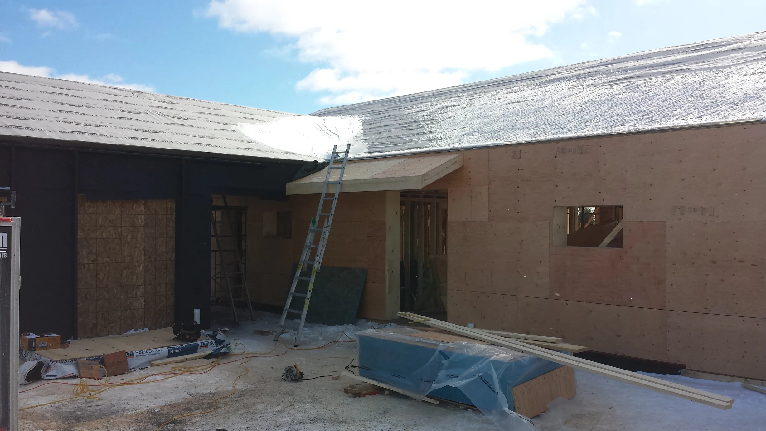 Deep Charcoal Interlock Standing Seam aluminum roof being installed on the home, replacing new construction, Cow Bay, Nova Scotia