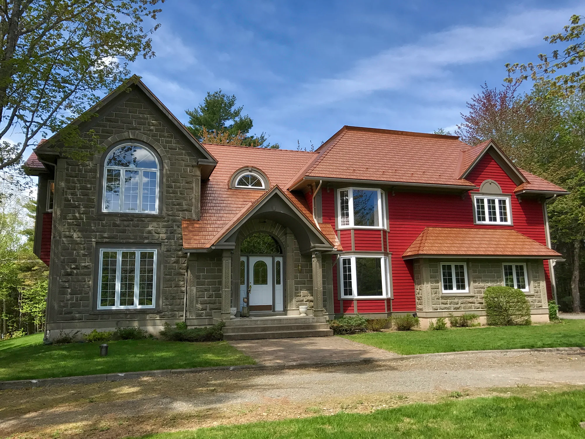 Black Interlock Slate aluminum roof on a red two-storey home with dormers among tall pines, Reids Hill (Shelburne), Nova Scotia