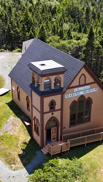 Black Interlock Slate aluminum roof on a church with a slate roof among trees by the ocean, Lahave, Nova Scotia