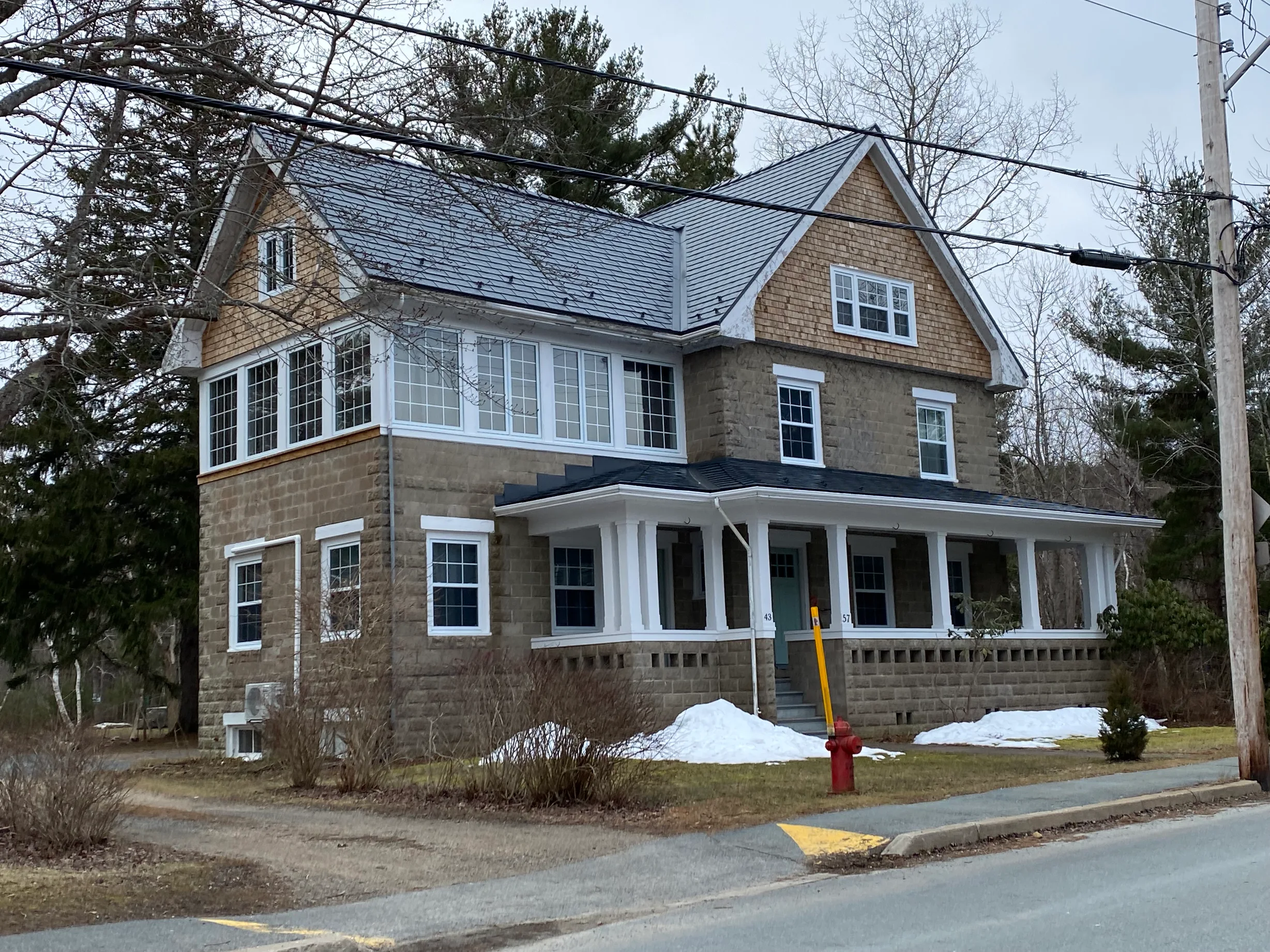 Deep Charcoal Interlock Slate aluminum roof on a brown two-storey home with dormers on a snow-covered, Mahone Bay, Nova Scotia