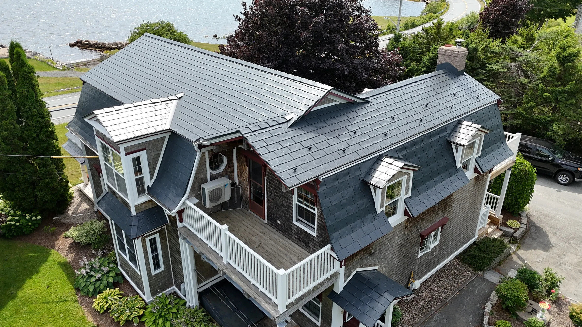 A colonial style home with a grey metal roof and white trim