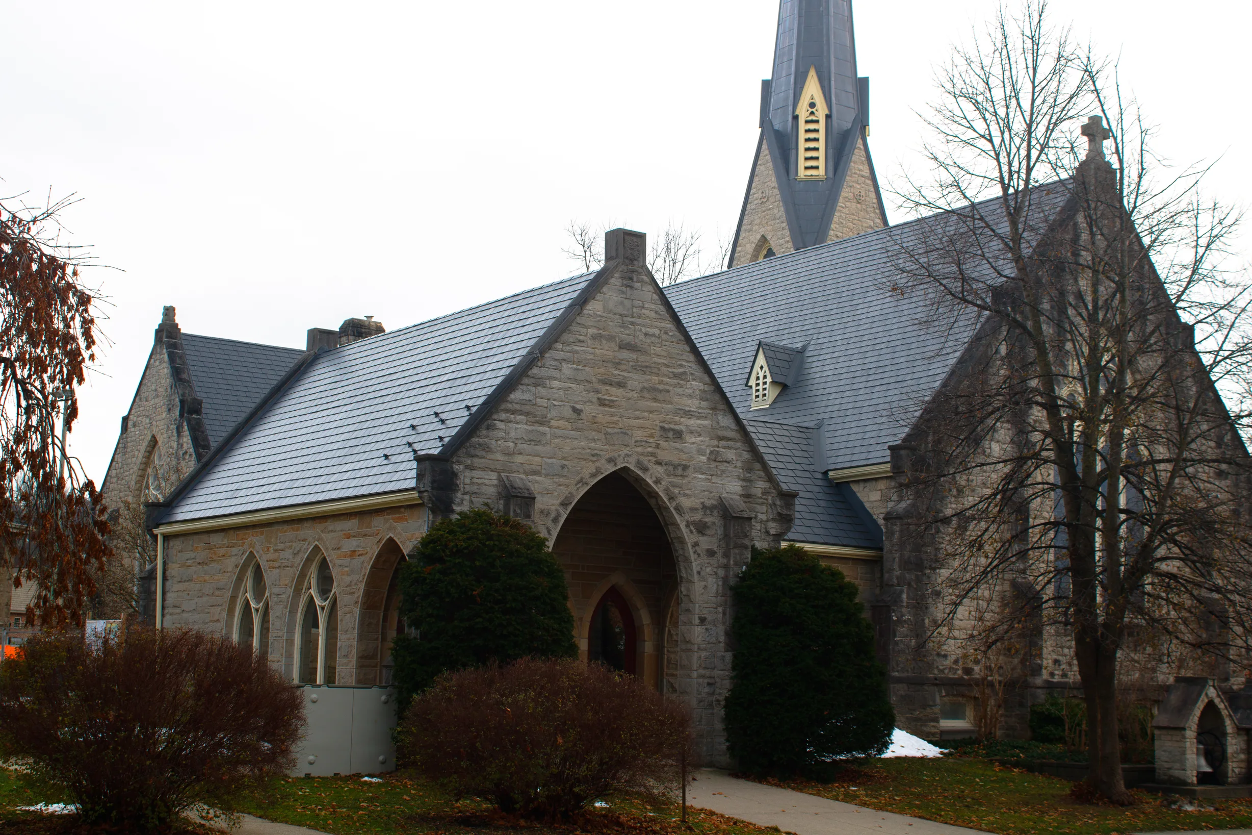 Charcoal Grey Interlock Slate aluminum roof on a grey stone church with a metal roof in a forested urban, Owen Sound, Ontario