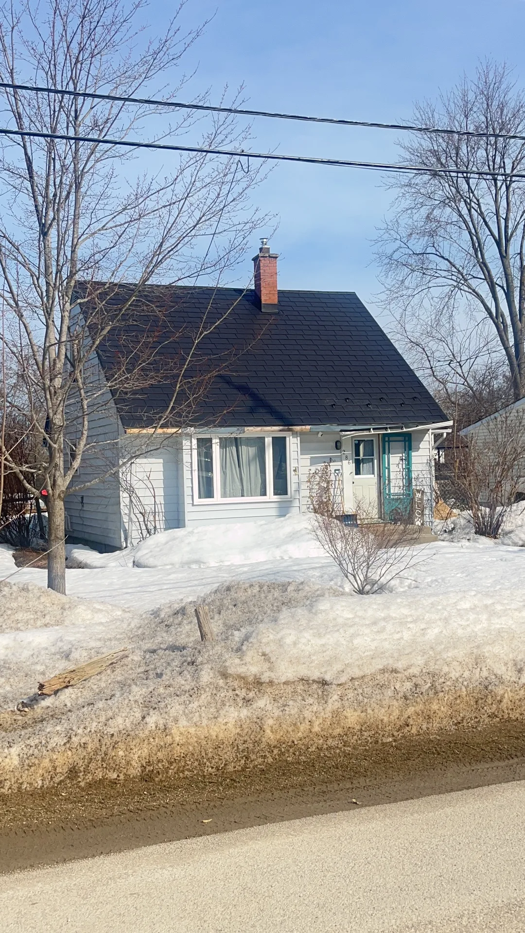 Black Interlock Slate aluminum roof on a white home with a metal roof in a snowy rural area, Meaford, Ontario
