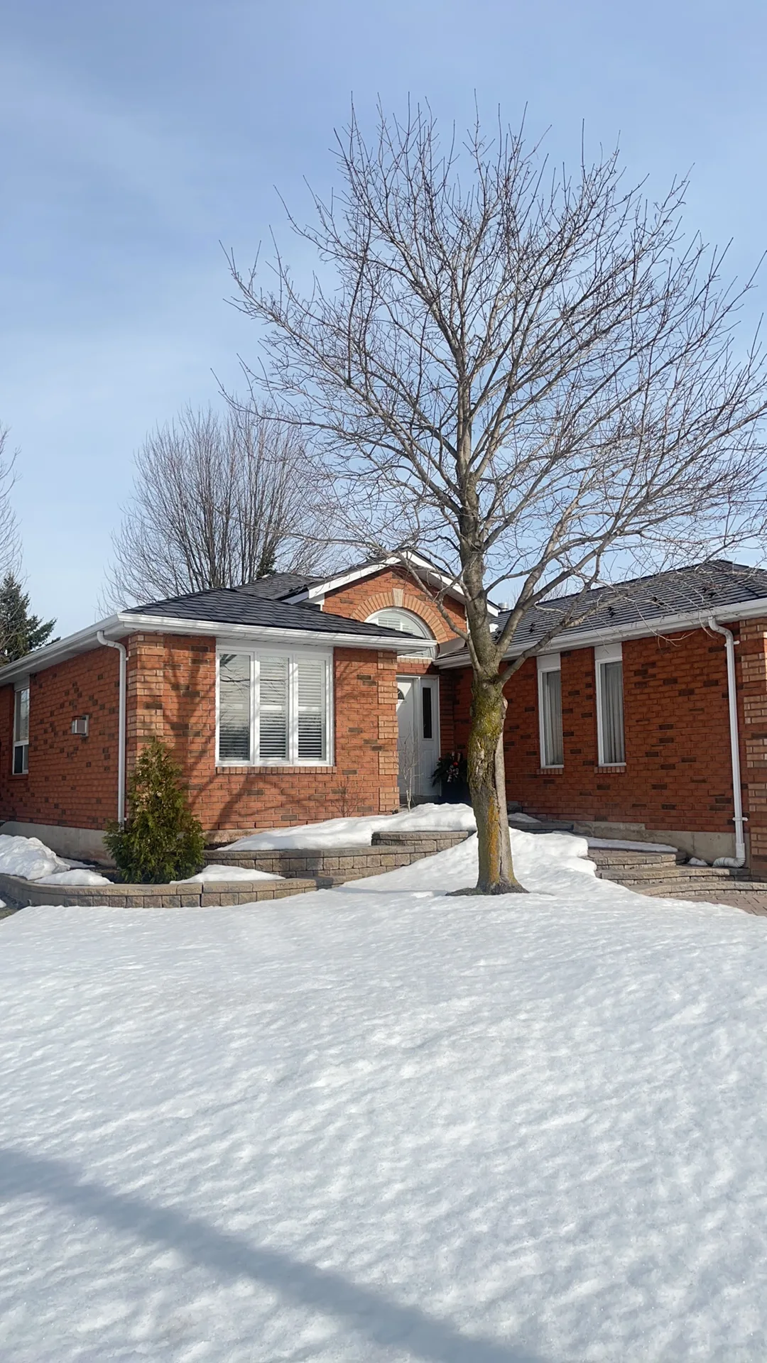 Tudor Brown Interlock Slate aluminum roof on a red brick home with a Tudor style among tall trees, Barrie, Ontario