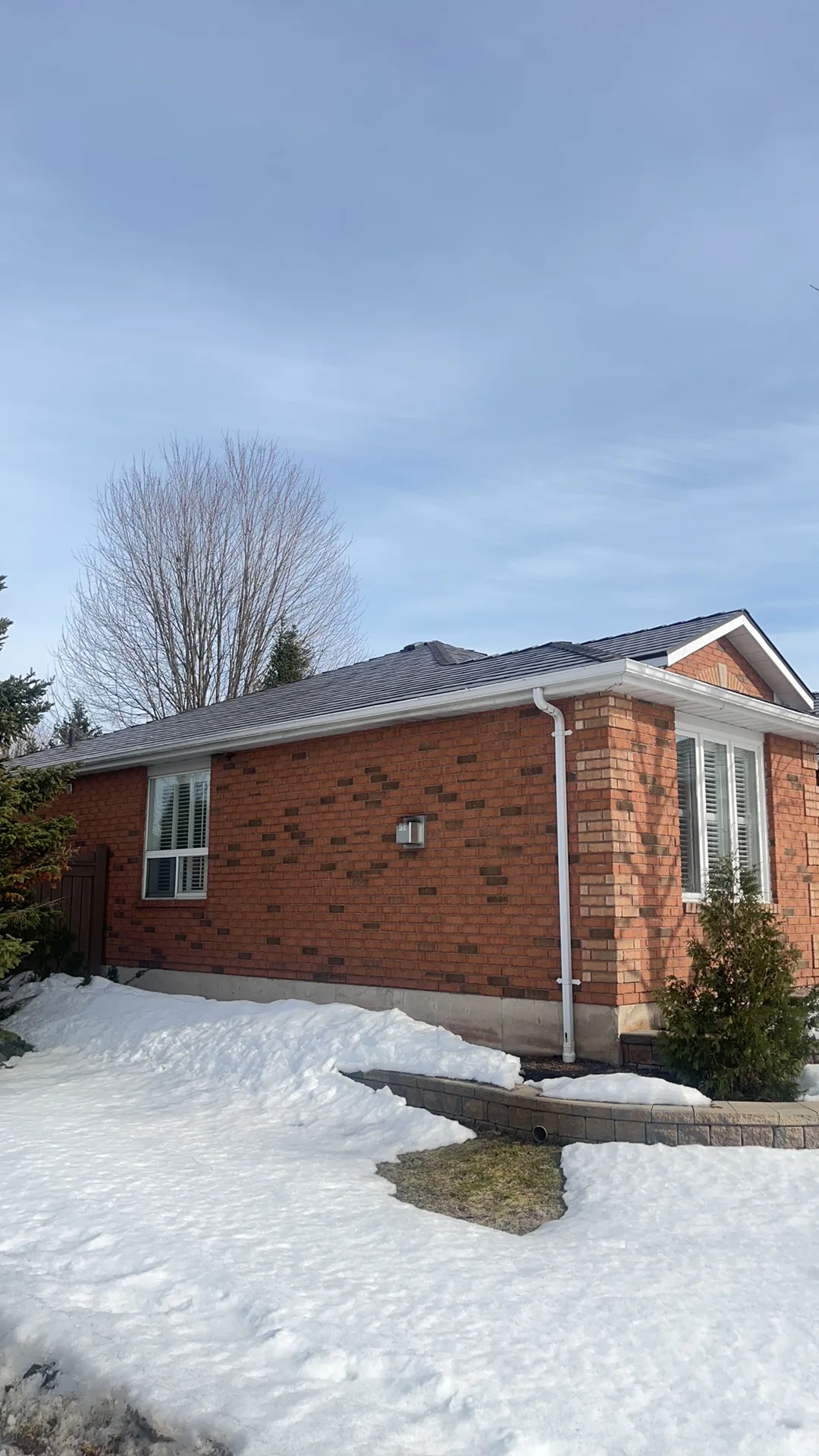 Tudor Brown Interlock Slate aluminum roof on a red brick home with a metal roof in a snowy suburban area, Barrie, Ontario