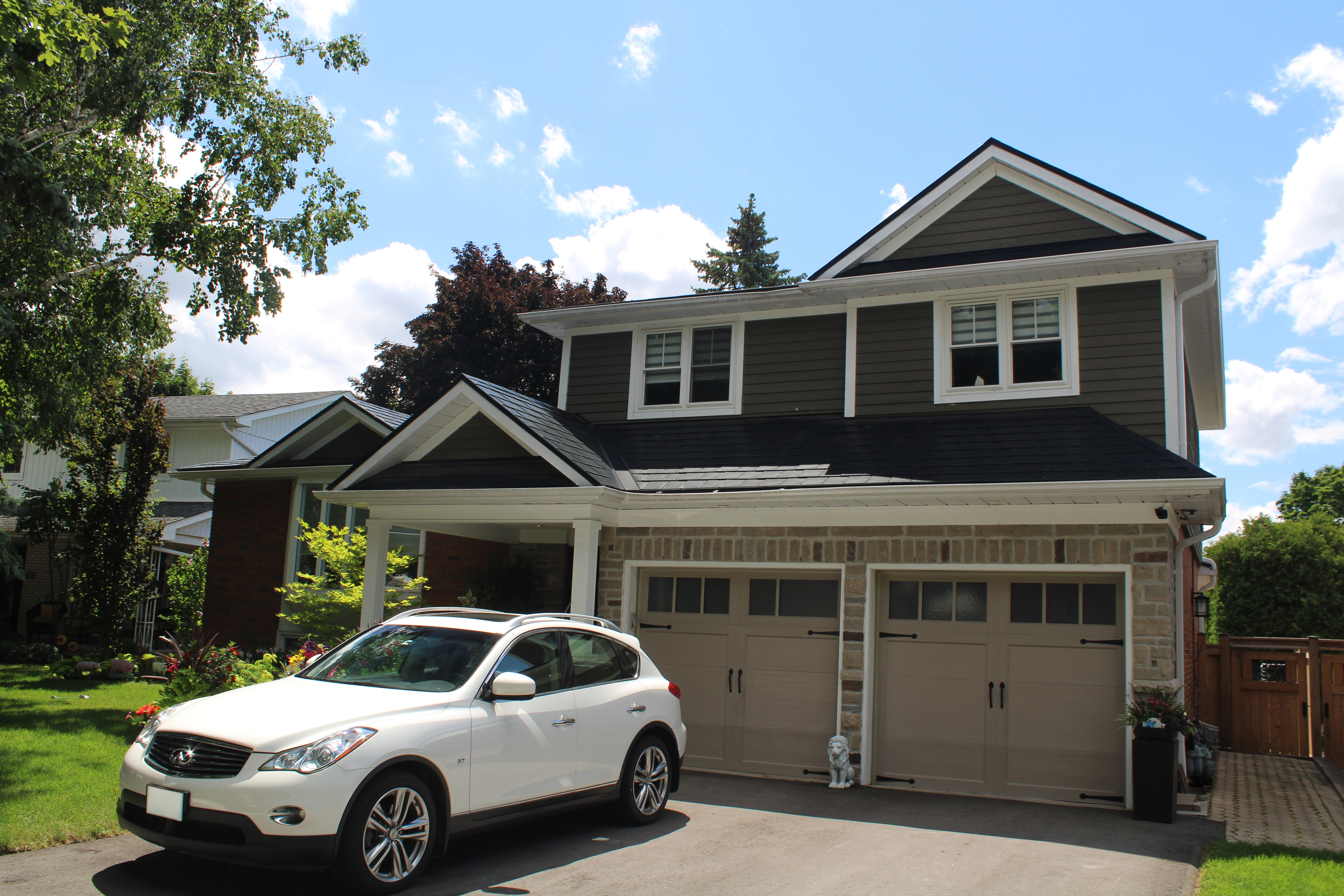 Two-storey Craftsman home in Markham ON featuring black Interlock aluminum slate metal roofing with complex multi-gable profile and stone facade.
