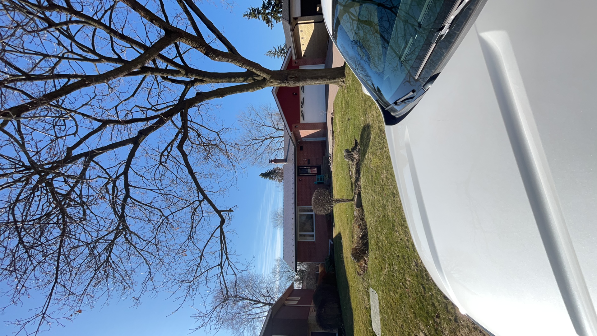Ranch-style brick home in Toronto with Interlock Musket Grey aluminum slate metal roof, low-pitched profile, attached garage, and mature bare tree in foreground.