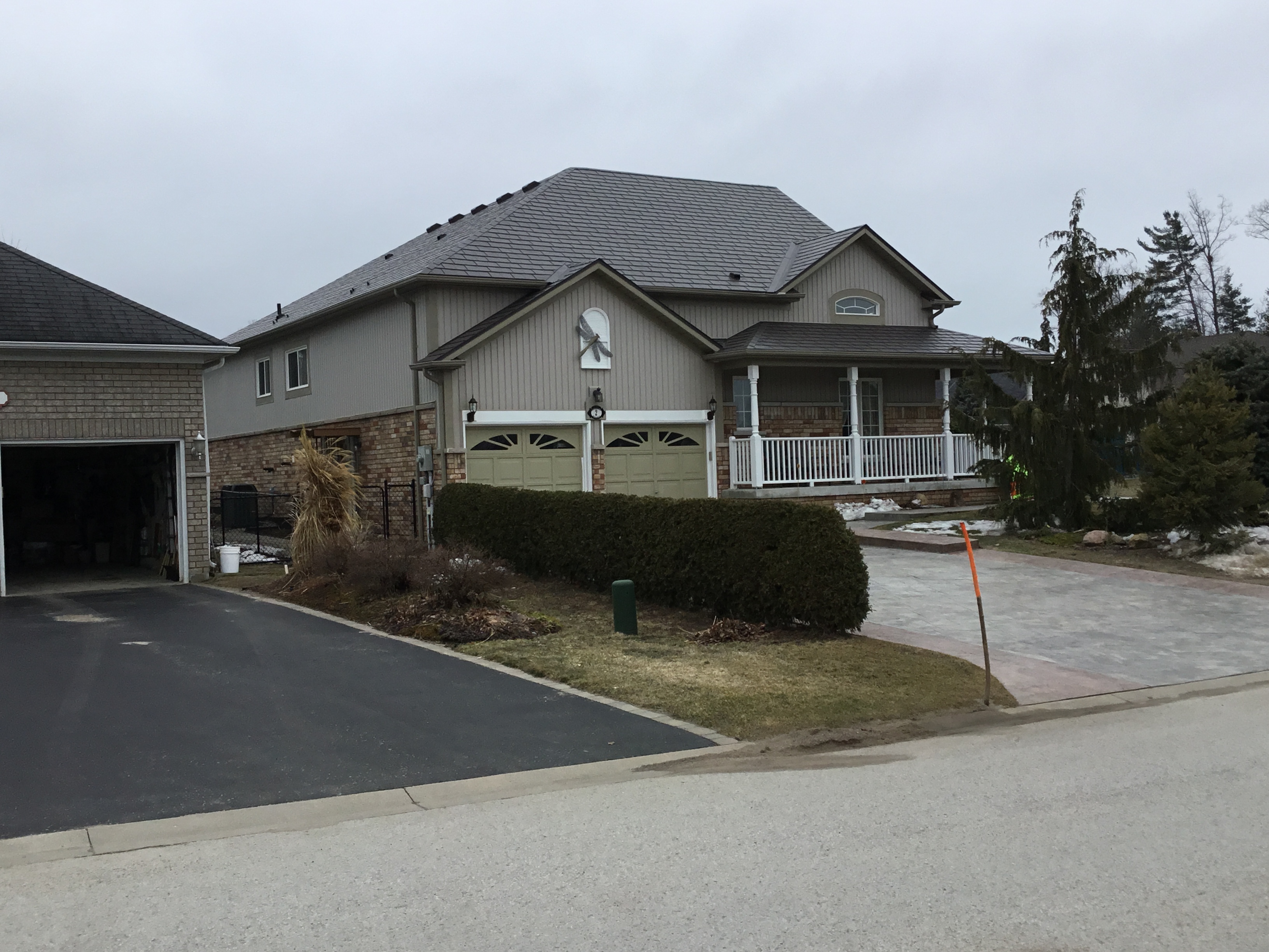 Craftsman-style home in Wasaga Beach with Interlock Tudor Brown aluminum slate roofing, multi-hip complex roof, covered front porch, and double garage.