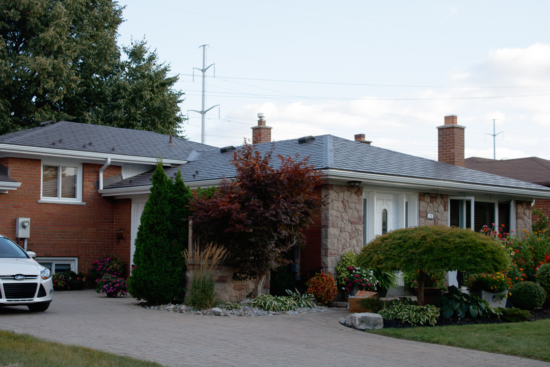 Single-storey ranch home in Scarborough with Interlock Tudor Brown aluminum slate metal roof, multiple chimneys, and well-landscaped front yard.