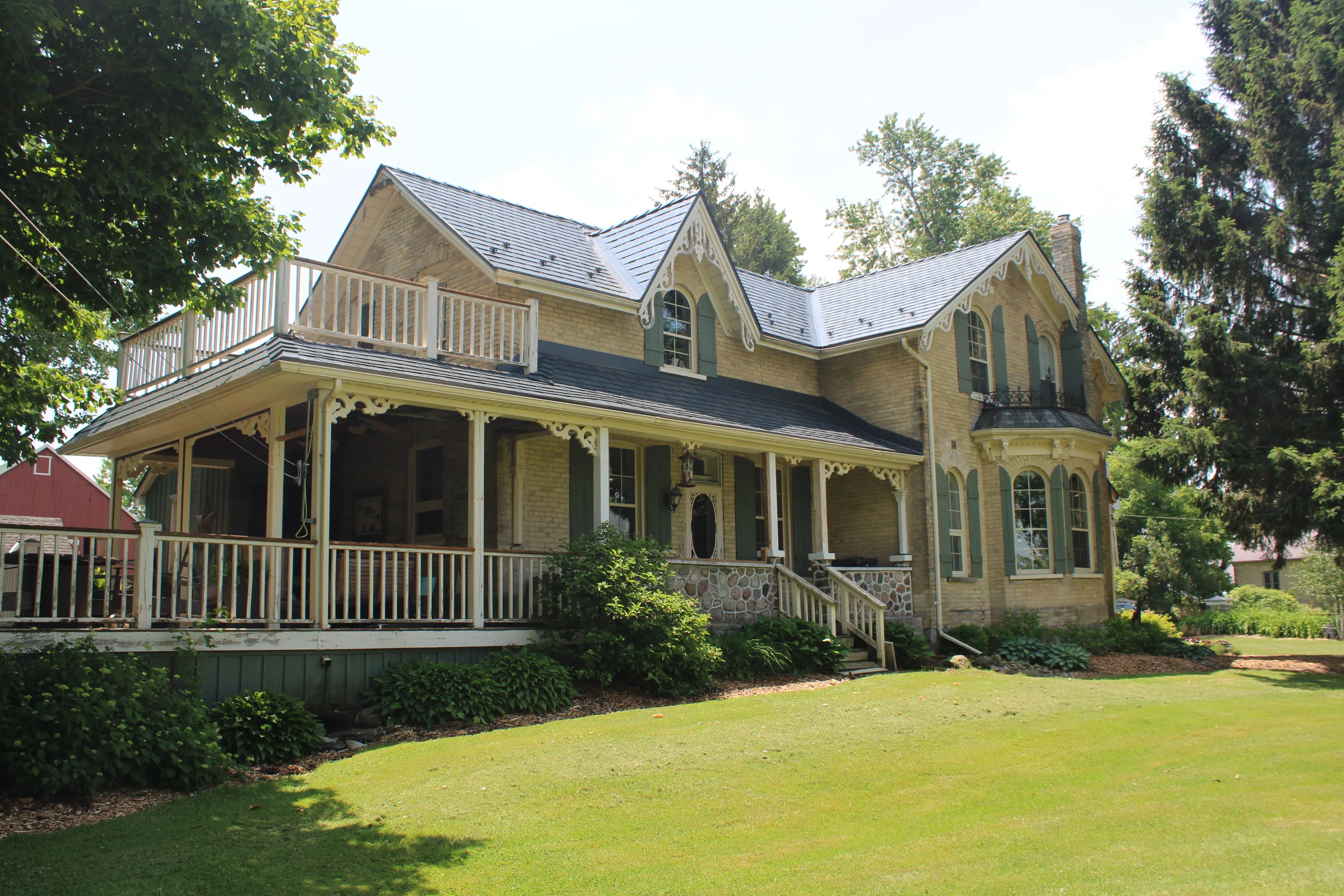 Deep Charcoal Interlock Cedar Shingle aluminum roof on a two-storey farmhouse with a porch and dormers among tall, Thorndale, Ontario