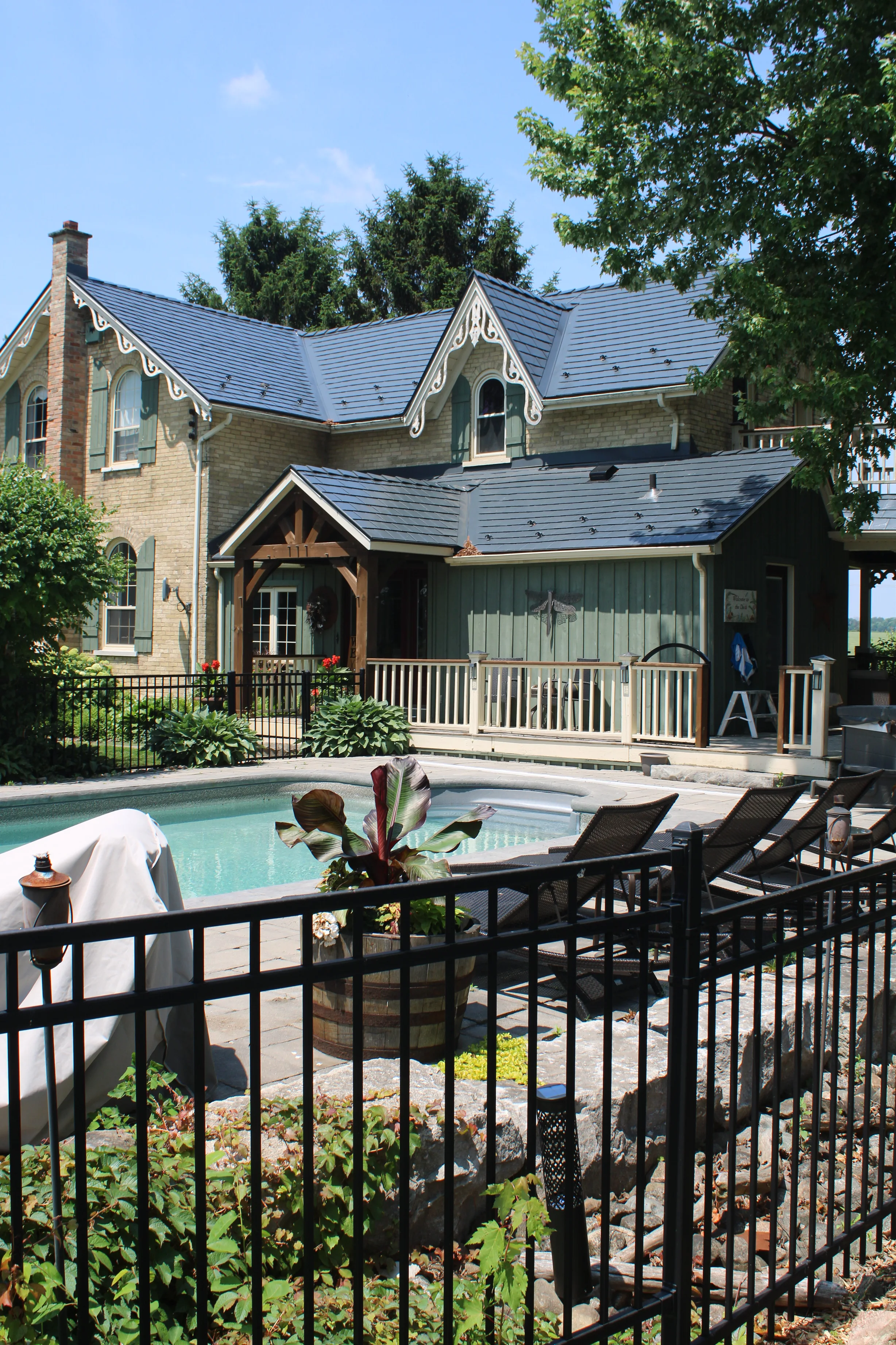 Deep Charcoal Interlock Cedar Shingle aluminum roof on a tan two-storey Victorian home with dormers among tall, Thorndale, Ontario