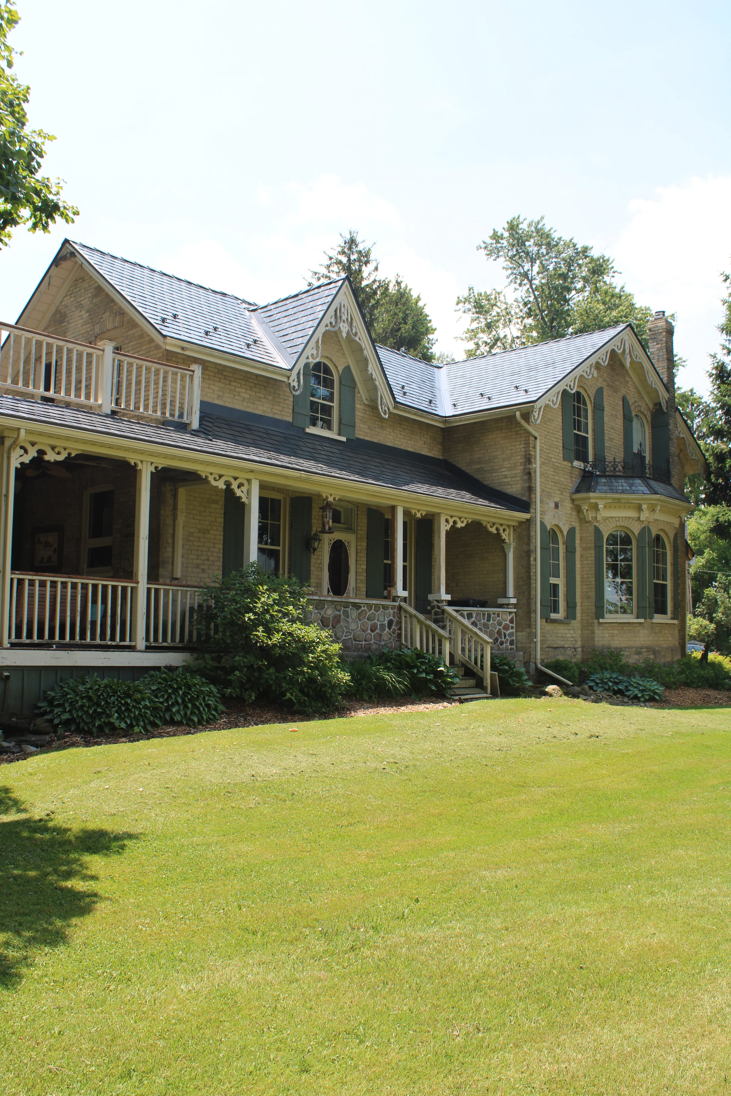 Deep Charcoal Interlock Cedar Shingle aluminum roof on a tan two-storey Victorian home with dormers in a forested, Thorndale, Ontario