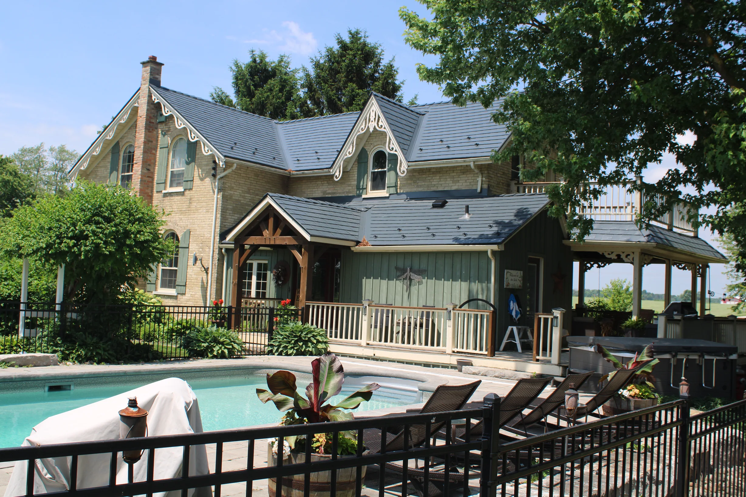 Deep Charcoal Interlock Cedar Shingle aluminum roof on a tan two-storey home with dormers among tall green trees, Thorndale, Ontario