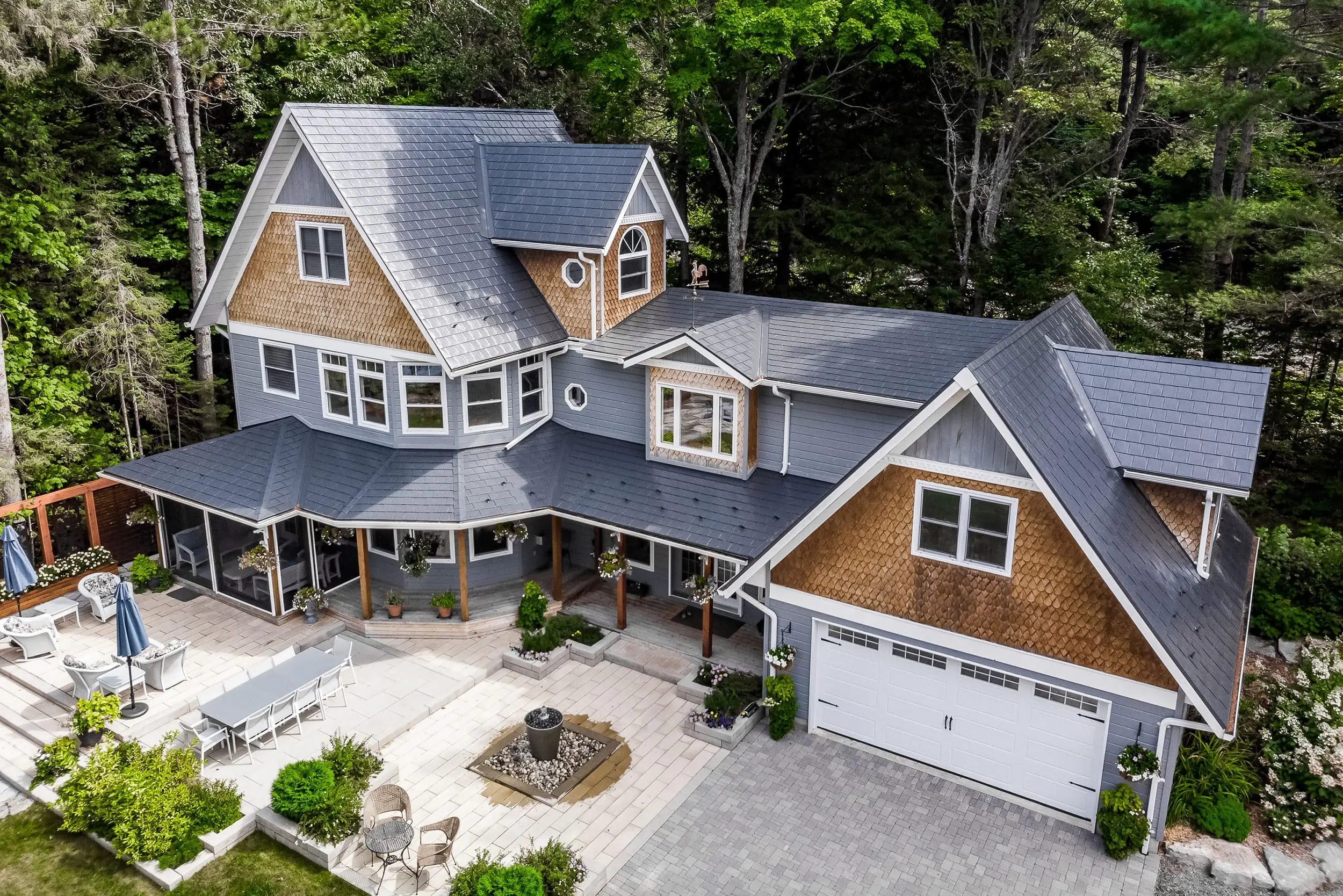 Aerial view of a Victorian-style home in Algonquin Highlands with a complex deep charcoal Interlock aluminum slate roof featuring dormers, turret, and multiple valleys.
