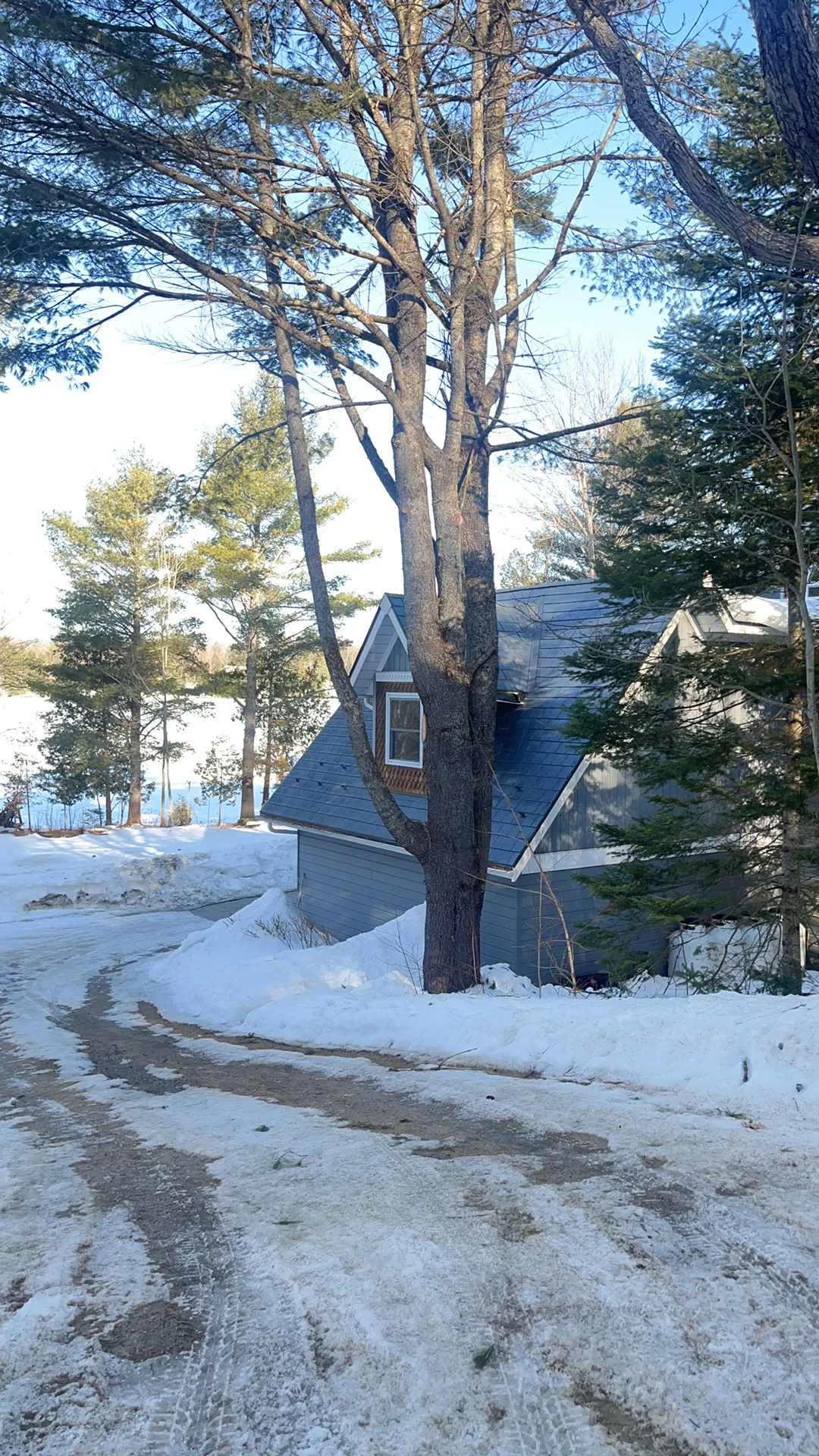 Deep Charcoal Interlock Slate aluminum roof being installed on a grey two-storey chalet with a metal roof on a snowy lake, Algonquin Highlands, Ontario