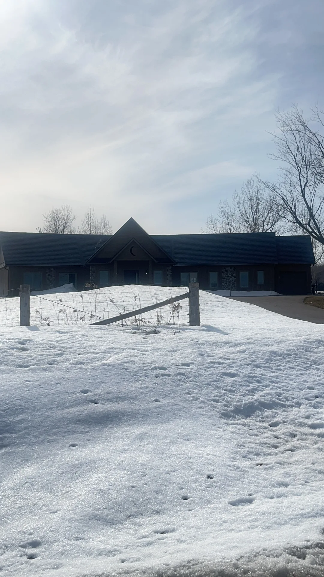 Deep Charcoal Interlock Slate aluminum roof on a black ranch-style home with a metal roof in a snowy rural, Springwater, Ontario