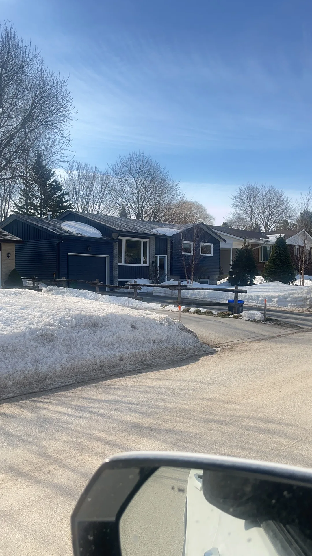 Tudor Brown Interlock Slate aluminum roof being installed on a blue single-family home in a rural suburb with snow on, Thornbury, Ontario