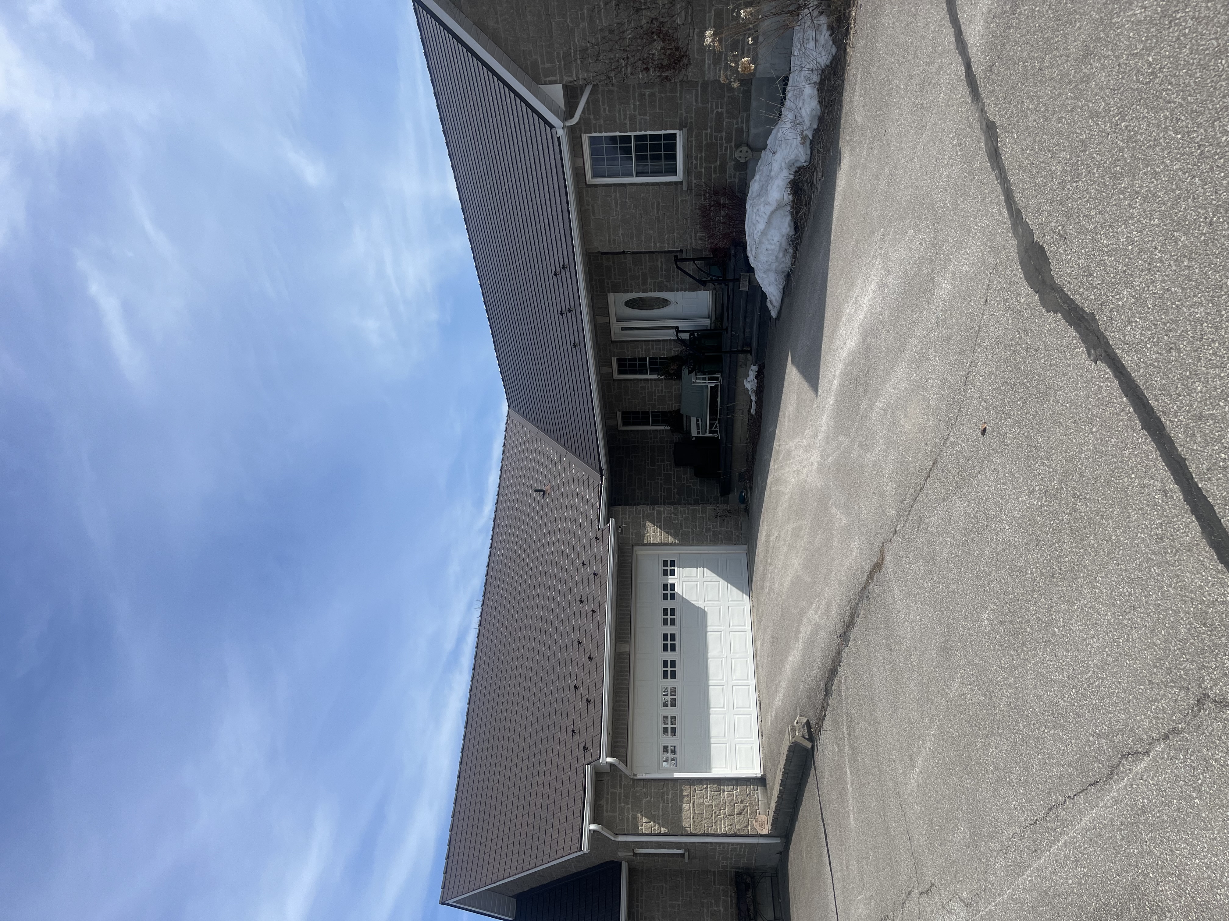 Single-storey brick ranch home in Innisfil, ON with Interlock Tudor Brown cedar shingle metal roof, wide driveway, and attached garage in winter.