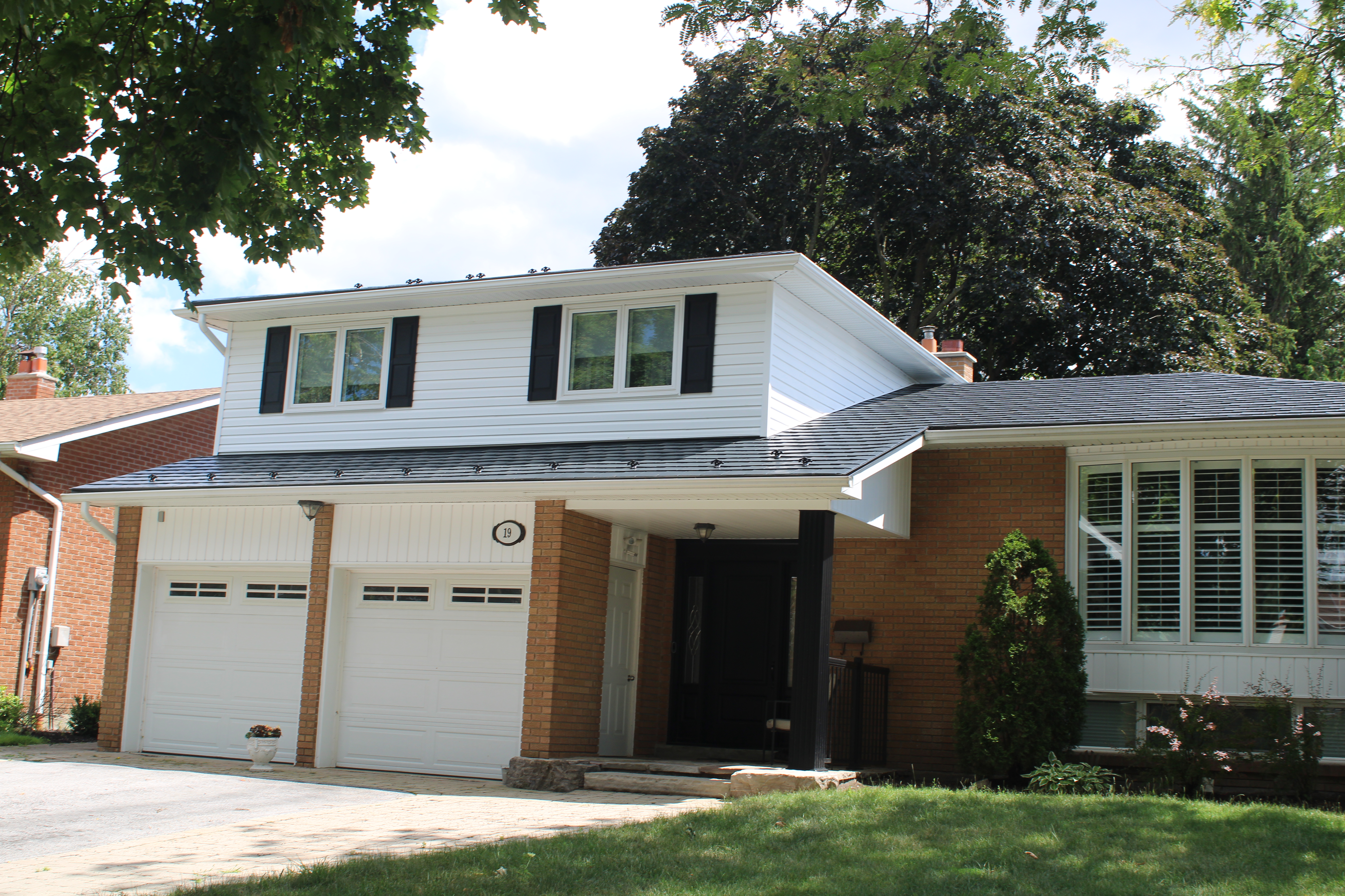 Two-storey brick Colonial home in Paris, ON with Interlock deep charcoal aluminum slate roof, box dormer, double garage, and black shutters.