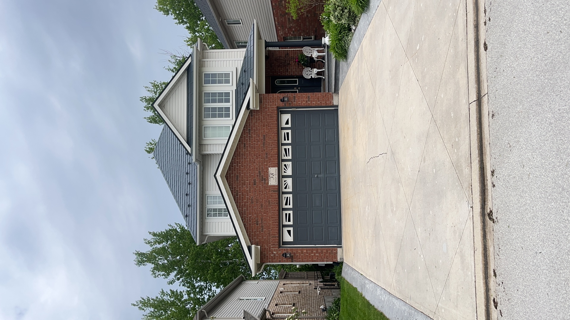 Two-storey brick home in Collingwood, ON with Interlock deep charcoal aluminum slate metal roofing on a multi-hip complex roof profile.