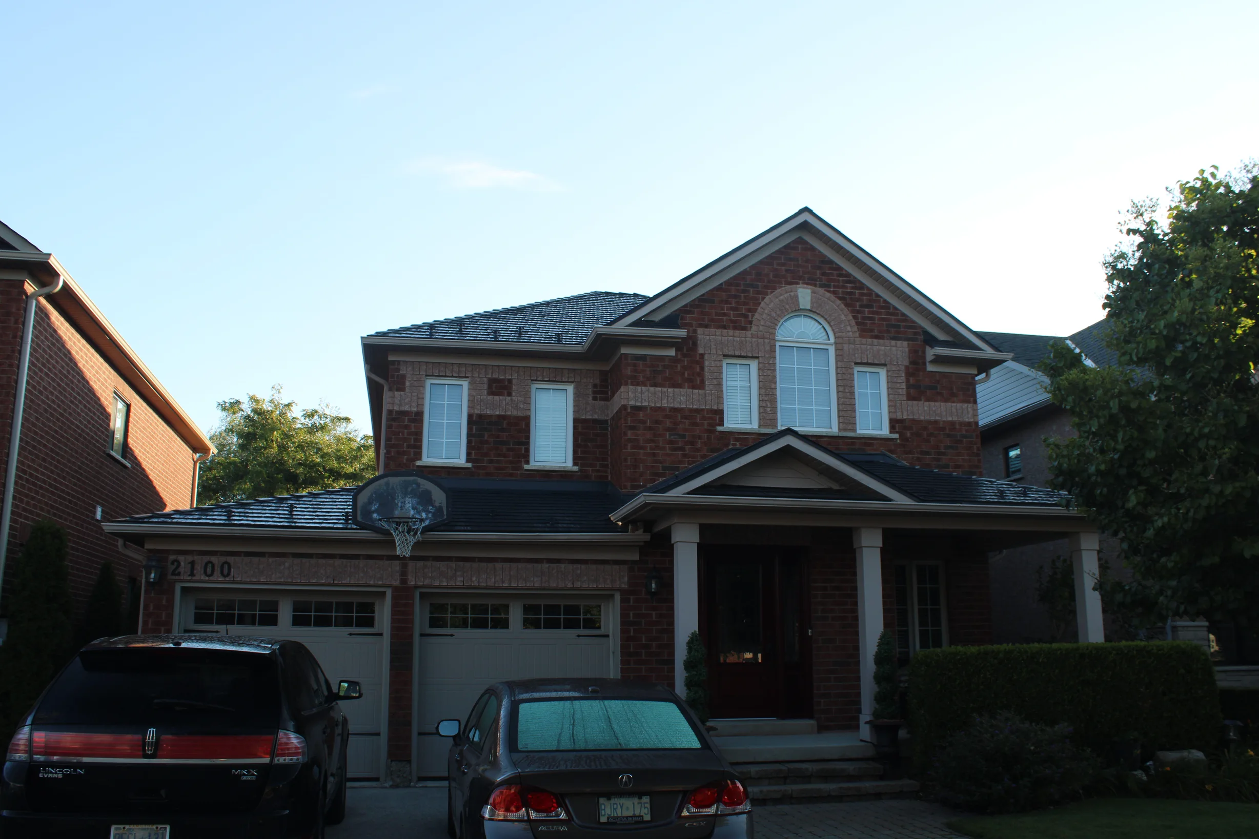 Musket Grey Interlock Slate aluminum roof on a two-storey brick home with a covered porch in a suburban, Caledonia, Ontario