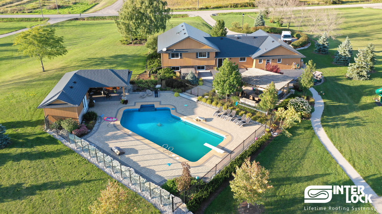 Aerial view of a large rural single-family home in Fenwick, ON featuring Interlock Deep Charcoal aluminum slate roofing across a complex multi-hip roof with a pool.