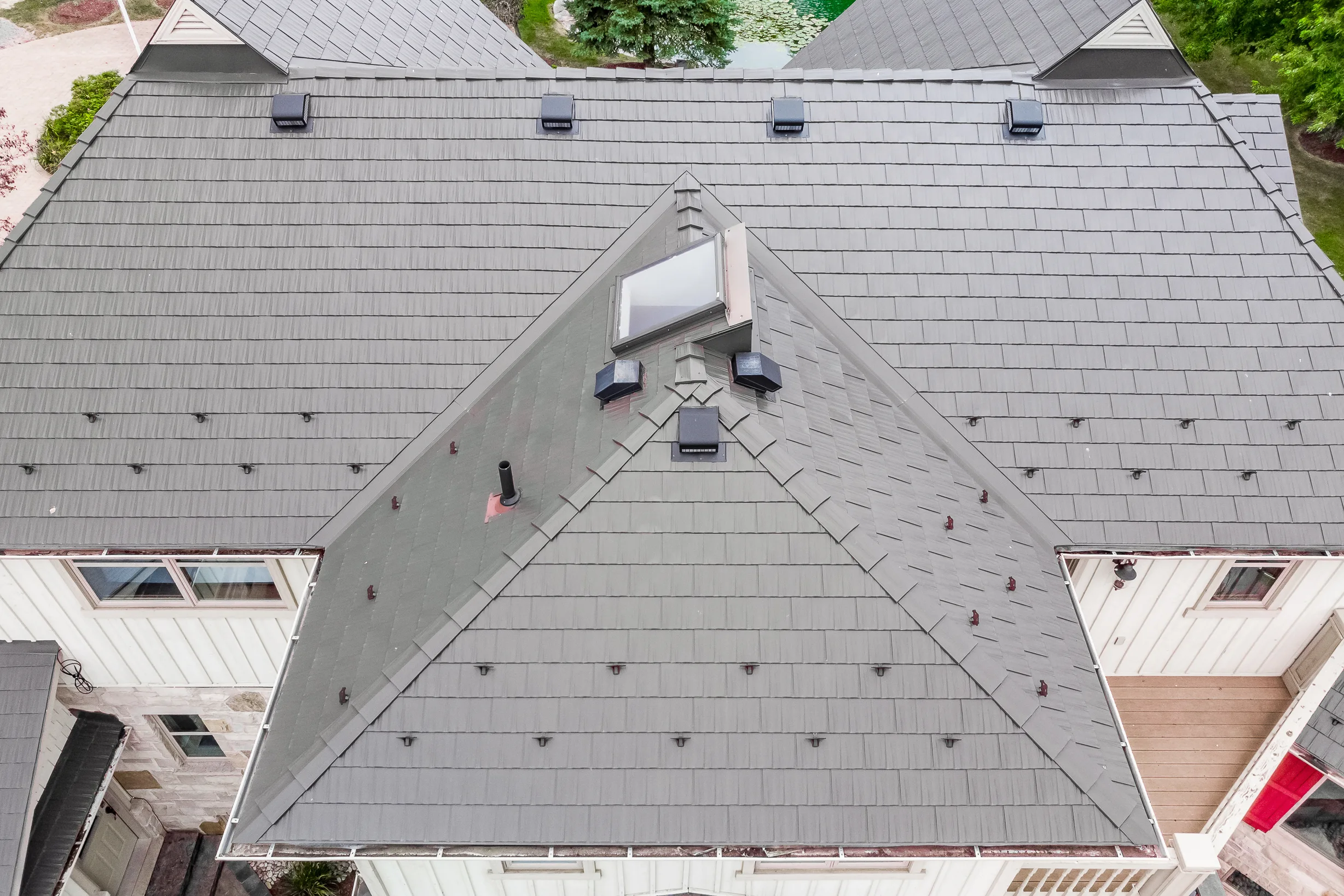 Tudor Brown Interlock Cedar Shingle aluminum roof on a Tudor-style home with a grey metal roof in a forested, Pefferlaw, Ontario