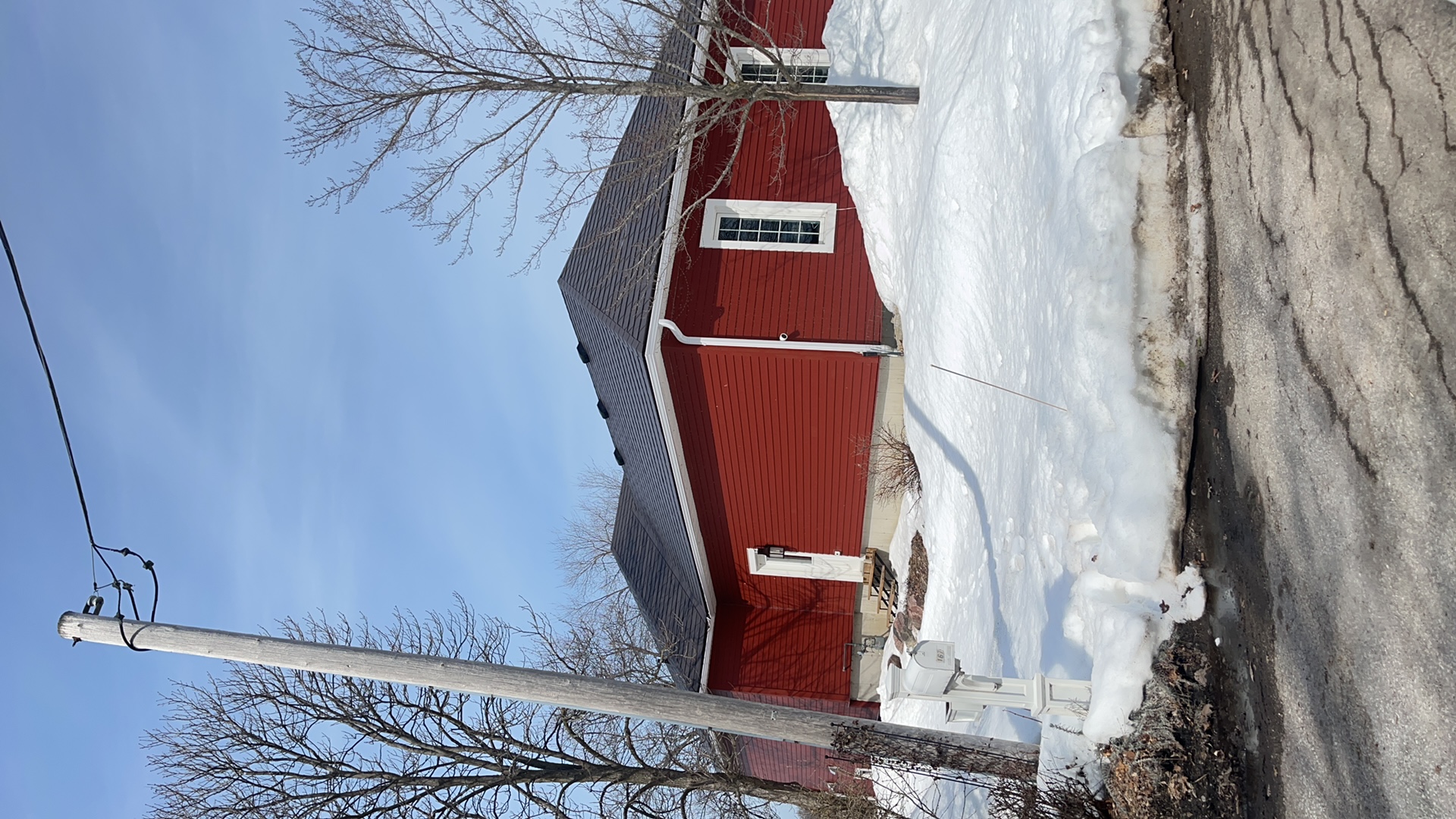Single-storey red ranch home with Interlock Tudor Brown aluminum slate hip roof, surrounded by deep winter snow in Orillia, ON.