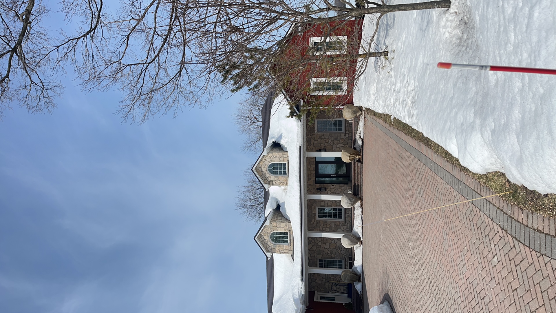 Tudor Brown Interlock aluminum slate roof with twin dormers on a 1.5-storey stone Colonial home in Orillia, ON, photographed in winter.