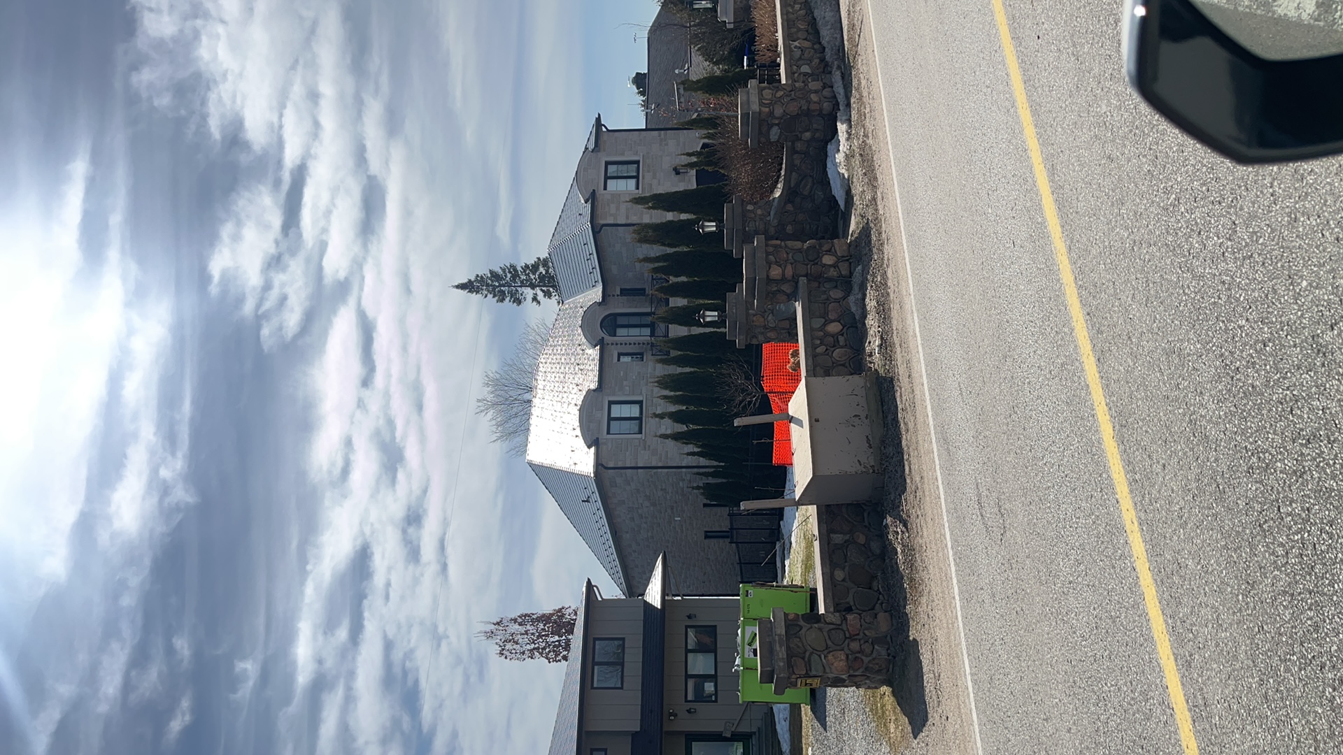 Street-view of a large two-storey stone Mediterranean home in Innisfil, ON with a steeply pitched multi-hip Deep Charcoal Interlock aluminum cedar shingle metal roof.