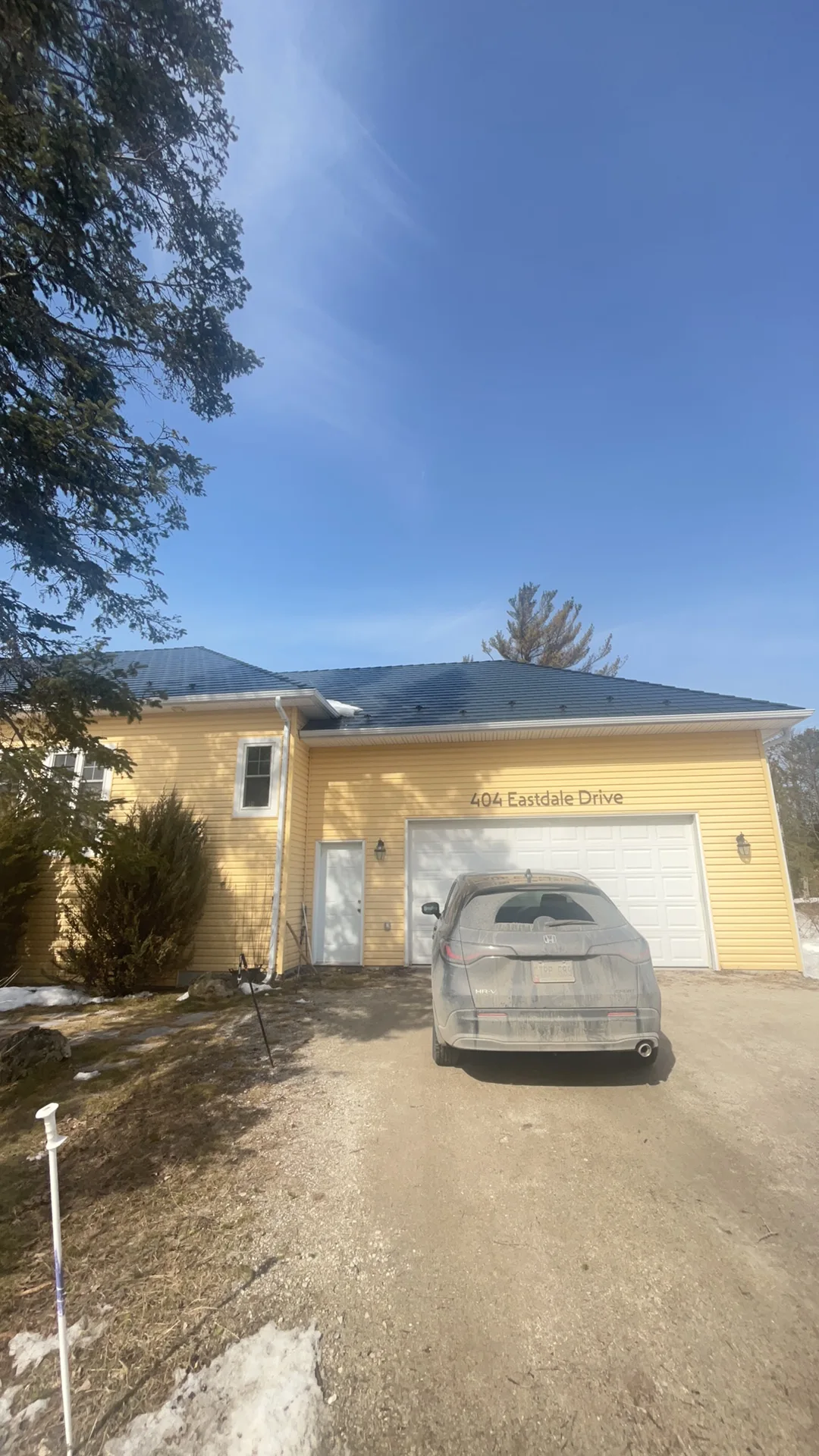 Deep Charcoal Interlock Cedar Shingle aluminum roof on a yellow home with a metal roof among tall pines, Wasaga Beach, Ontario