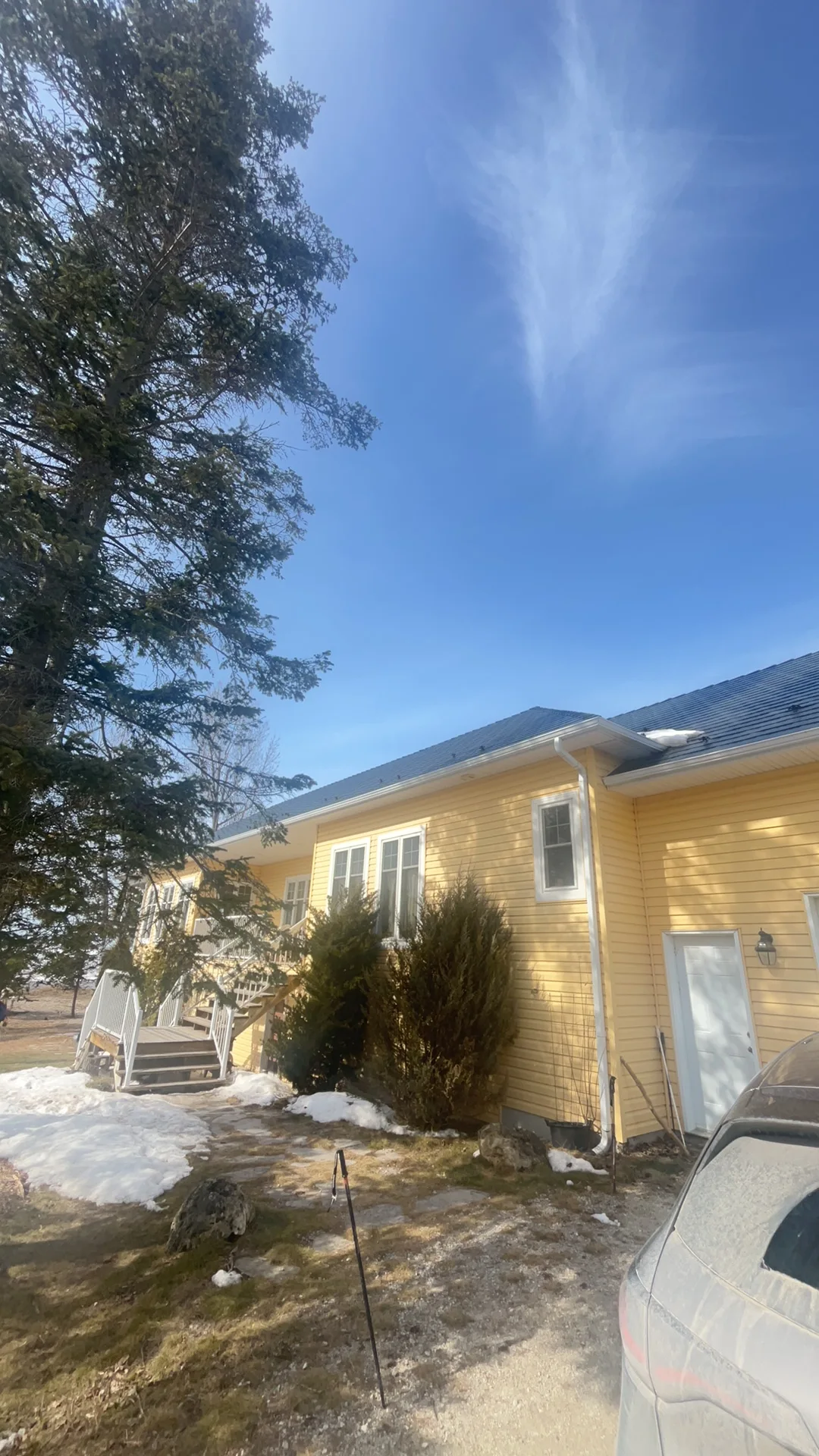 Deep Charcoal Interlock Cedar Shingle aluminum roof on a yellow ranch style home with a metal roof among tall pines, Wasaga Beach, Ontario
