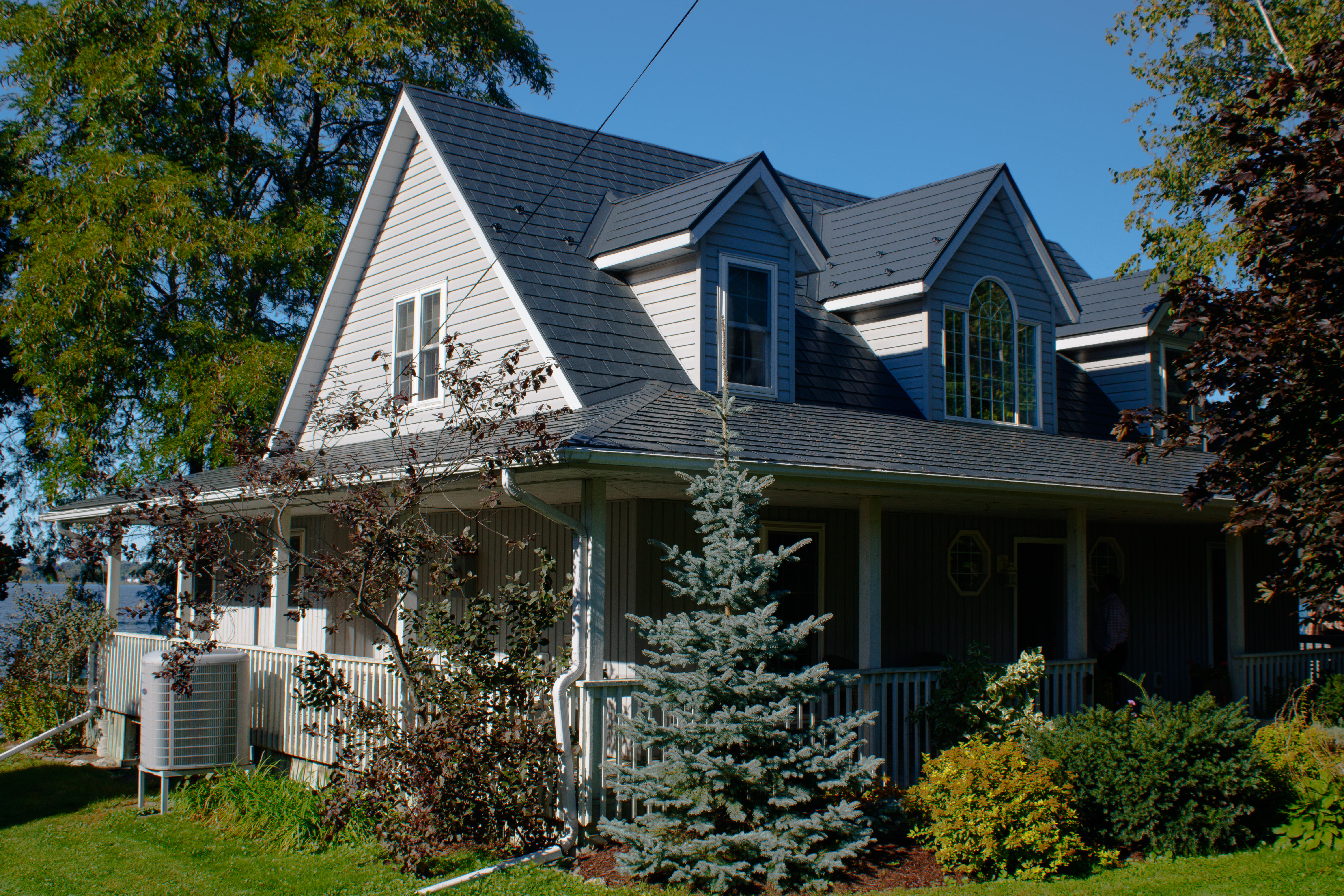 1.5-storey Victorian home in Cannifton ON with Interlock deep charcoal aluminum slate roofing, multiple dormers, complex multi-gable roofline, and wrap-around porch.