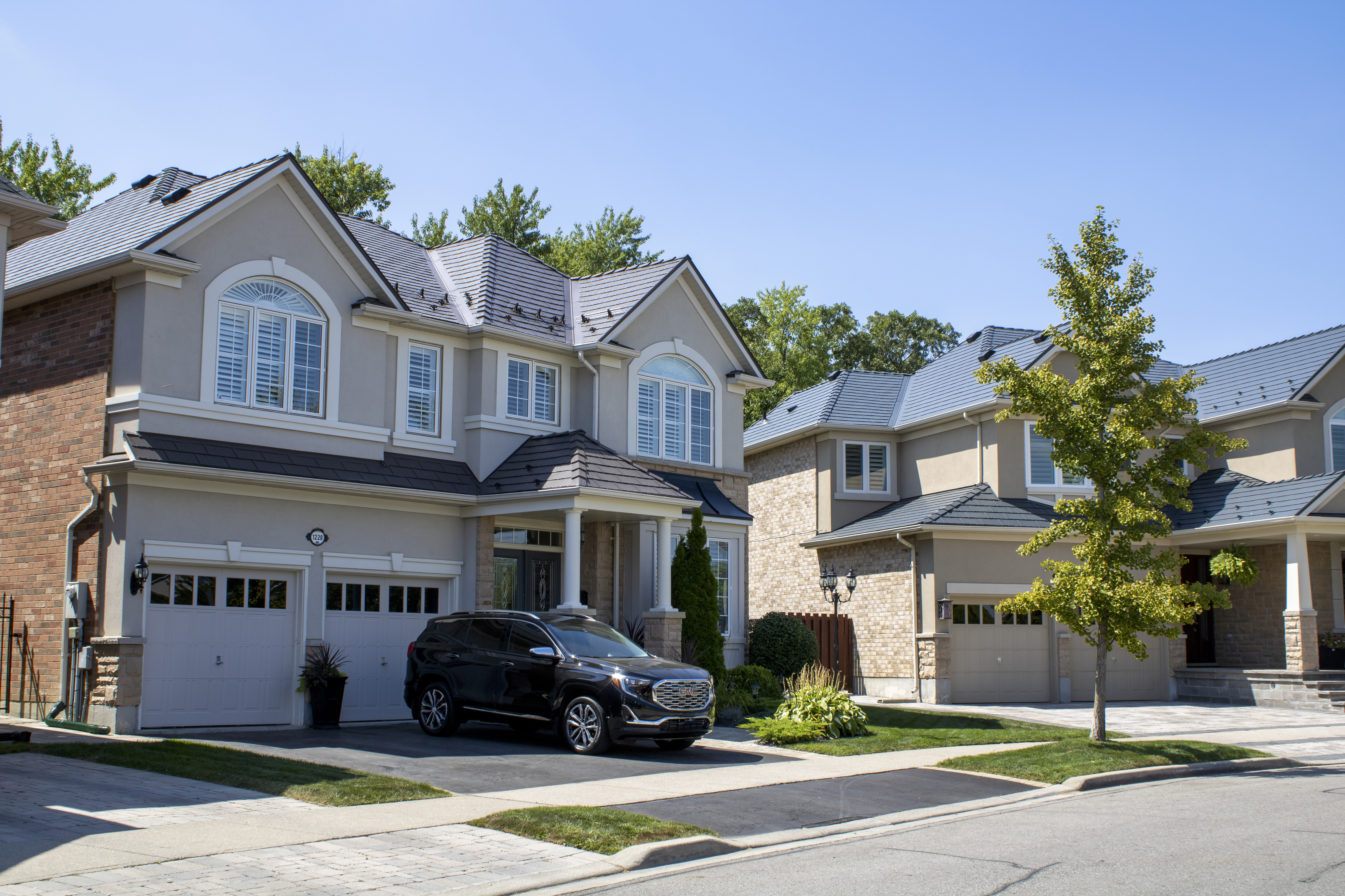 Two-storey Colonial-style homes in Milton, ON featuring Interlock Tudor Brown cedar shingle aluminum metal roofing with multi-hip complex roof profiles.