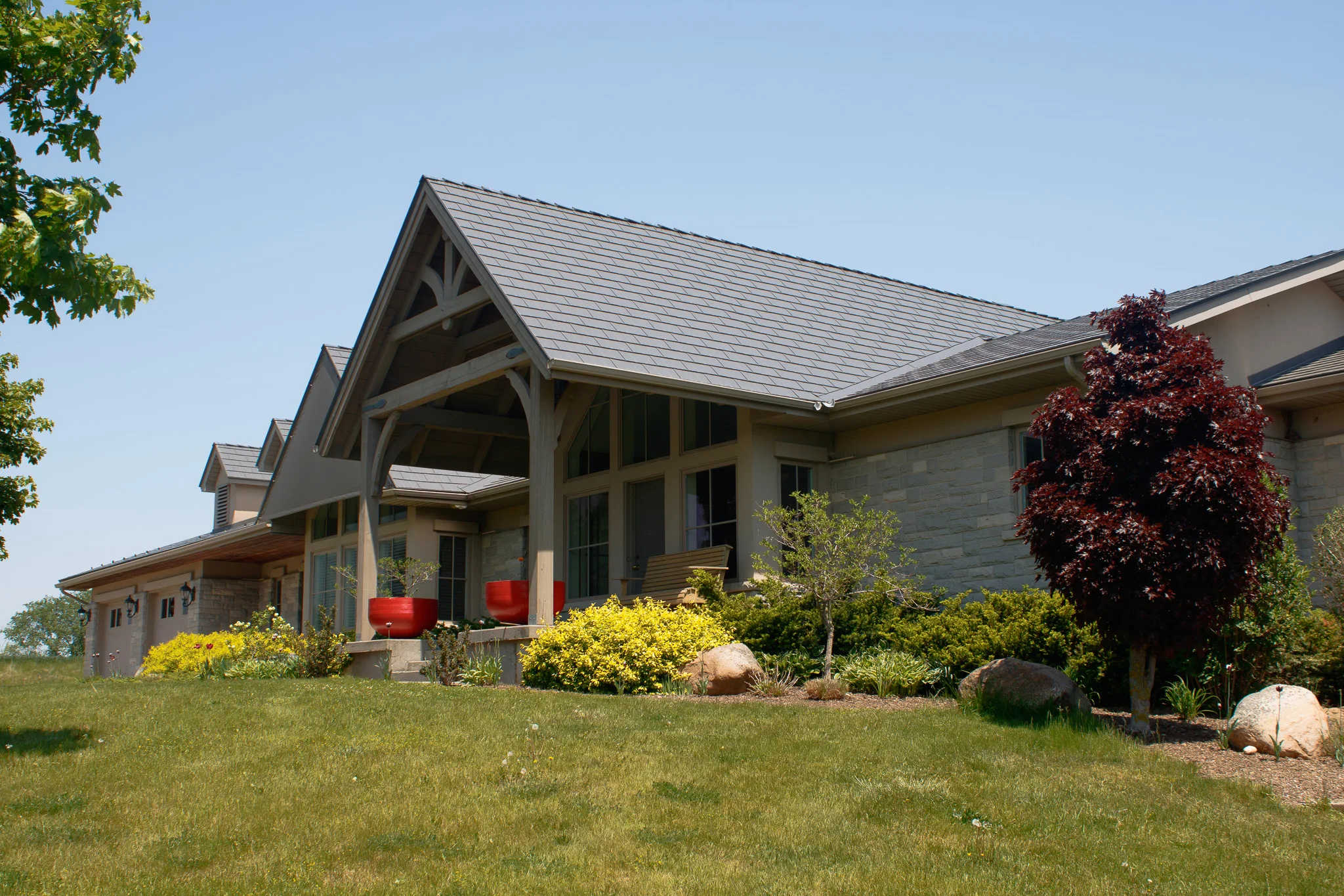 Musket Grey Interlock Cedar Shingle aluminum roof on a grey single-storey home with a gable roof among lush, Guelph, Ontario