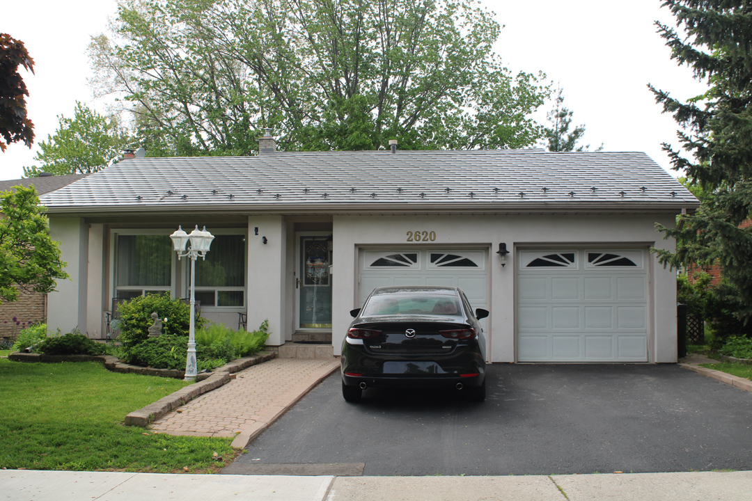 Single-storey ranch home in Mississauga with Interlock aluminum slate roof in Musket Grey, double garage, and brick-paved front walkway.
