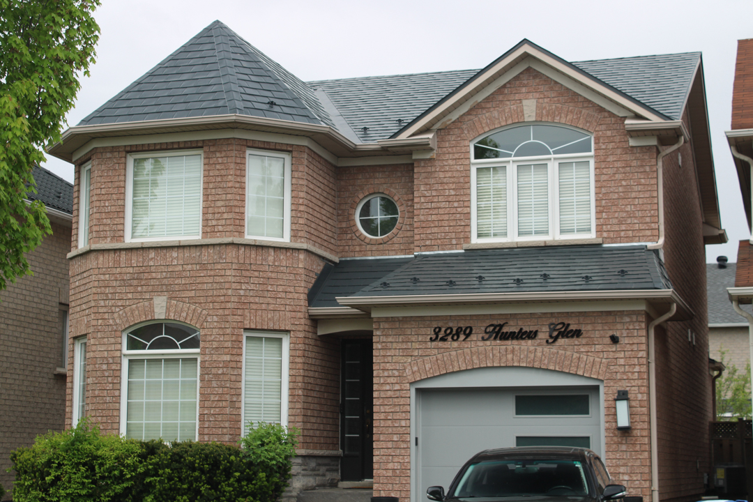 Two-storey brick Colonial home at 3289 Hunters Glen with deep charcoal Interlock aluminum slate roofing, prominent corner turret, and multi-hip complex roofline.