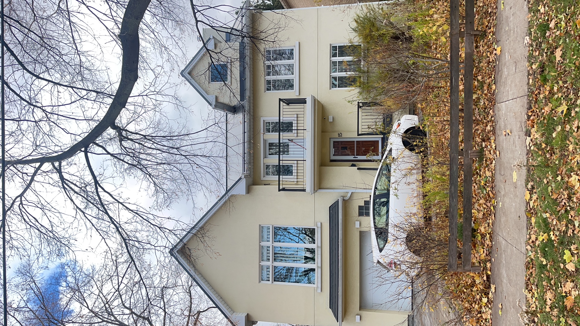 Front elevation of a 2-storey modern home in Etobicoke with deep charcoal standing seam metal roofing, dormers, and a second-floor balcony.