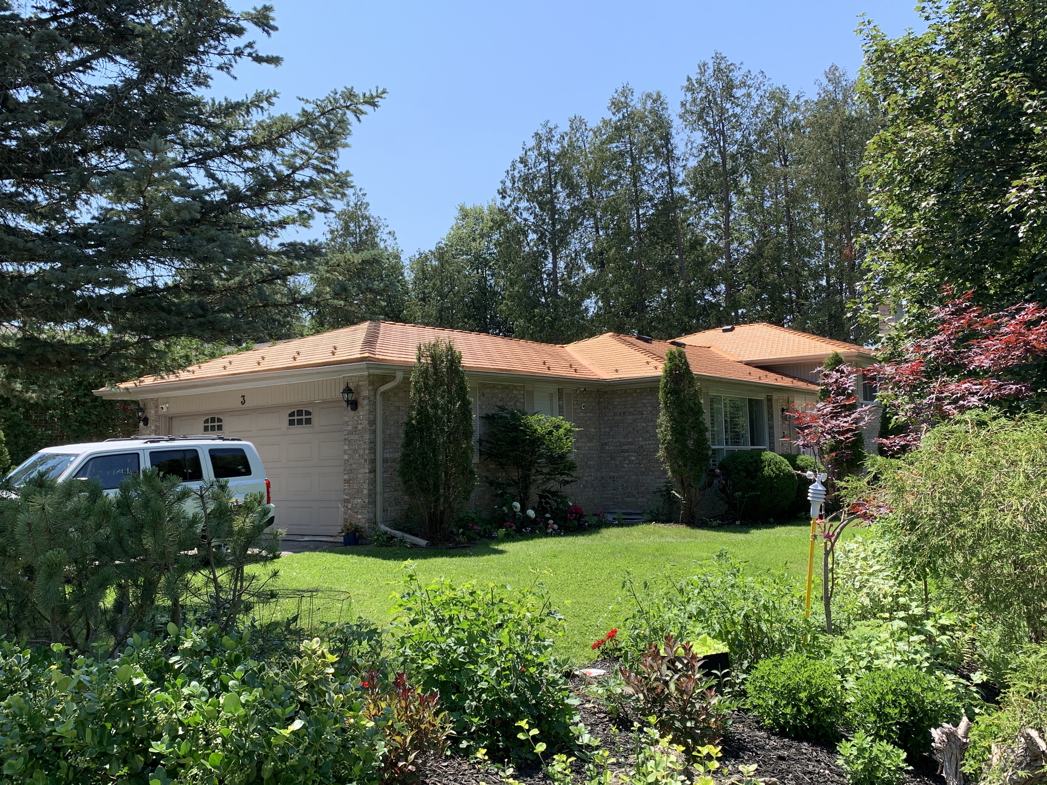 Single-storey ranch home in Aurora, ON with Interlock Copper Penny cedar-shingle aluminum roof over multi-hip roofline, surrounded by mature trees.