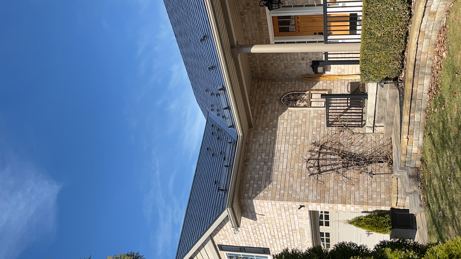 Black Interlock aluminum slate metal roof on a two-storey brick Colonial home in Cobourg, ON, featuring snow guards and complex multi-hip rooflines.