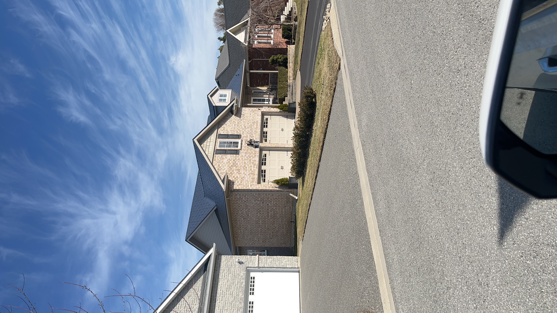 Street view of a 1.5-storey Craftsman-style brick home in Cobourg, ON featuring a black Interlock aluminum slate metal roof with multi-hip complexity.