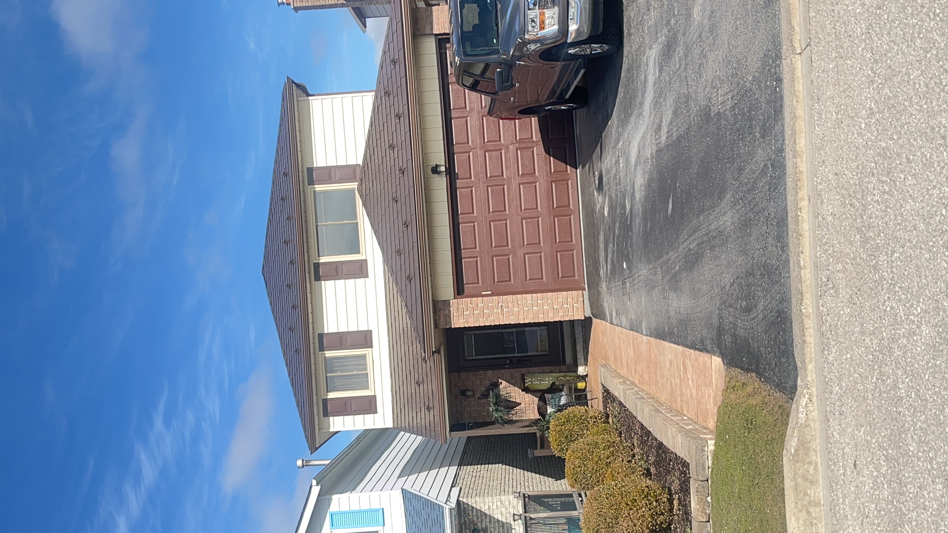 Two-storey suburban home in Bradford, ON with Interlock Colonial Brown aluminum slate metal roofing on a hip-style roof, paired with brick facade and brown garage door.