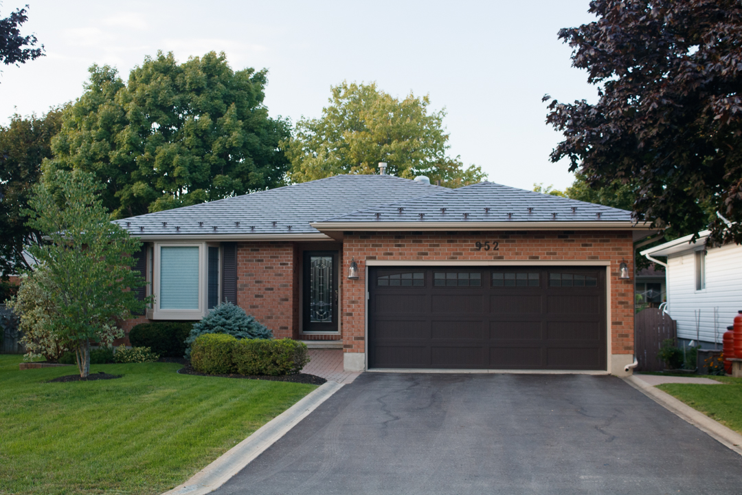 Single-storey brick ranch home at 952 with a Colonial Brown Interlock aluminum slate hip roof, double garage, and manicured front yard.