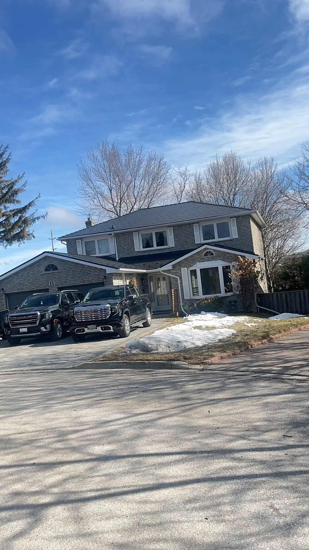 Black Interlock Slate aluminum roof on a two-storey brick home with a metal roof among trees and a, Bradford, Ontario