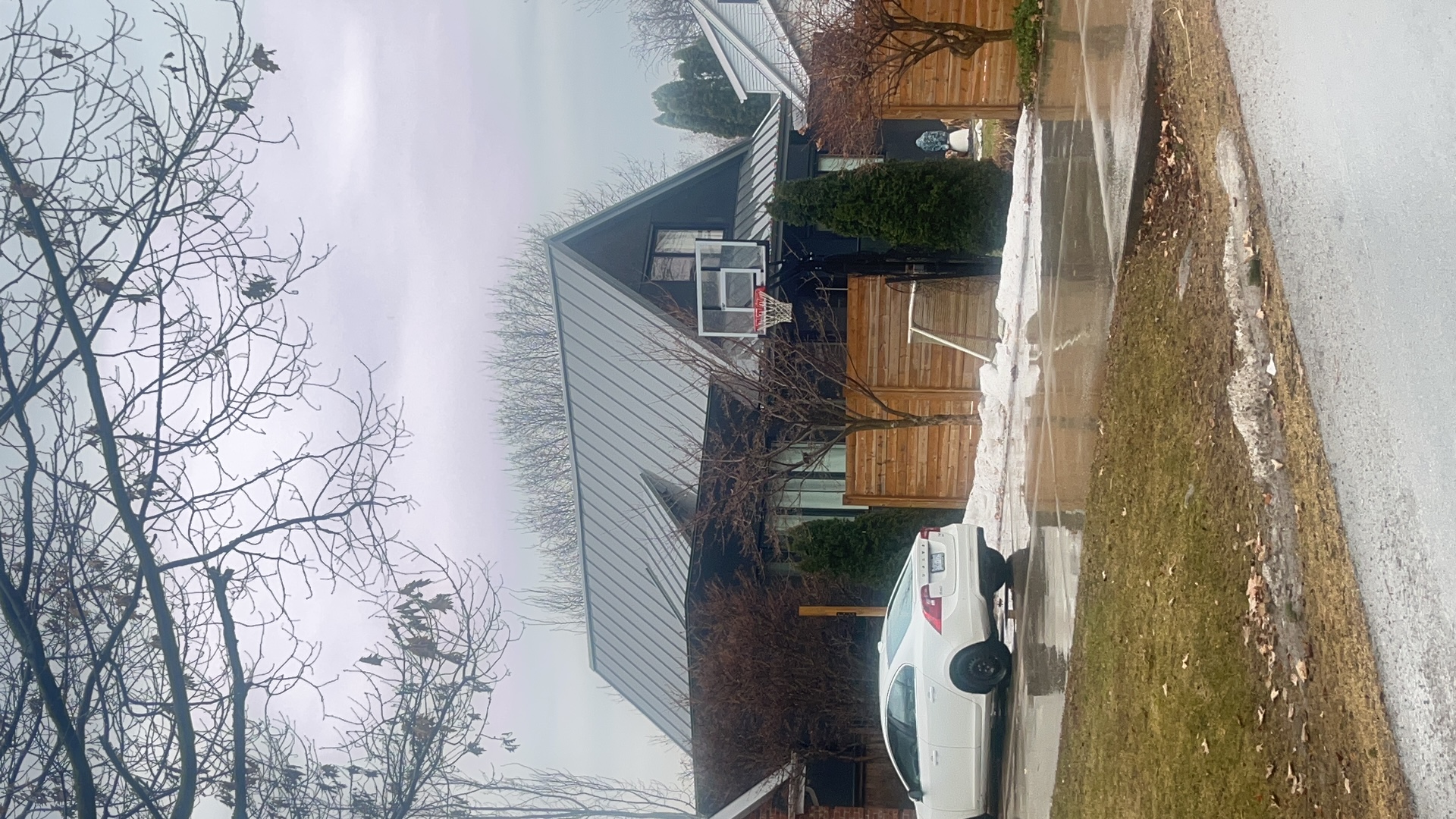 Steep A-frame home with Interlock Musket Grey standing seam metal roof, cedar fence, and basketball hoop in a suburban Burlington neighbourhood.