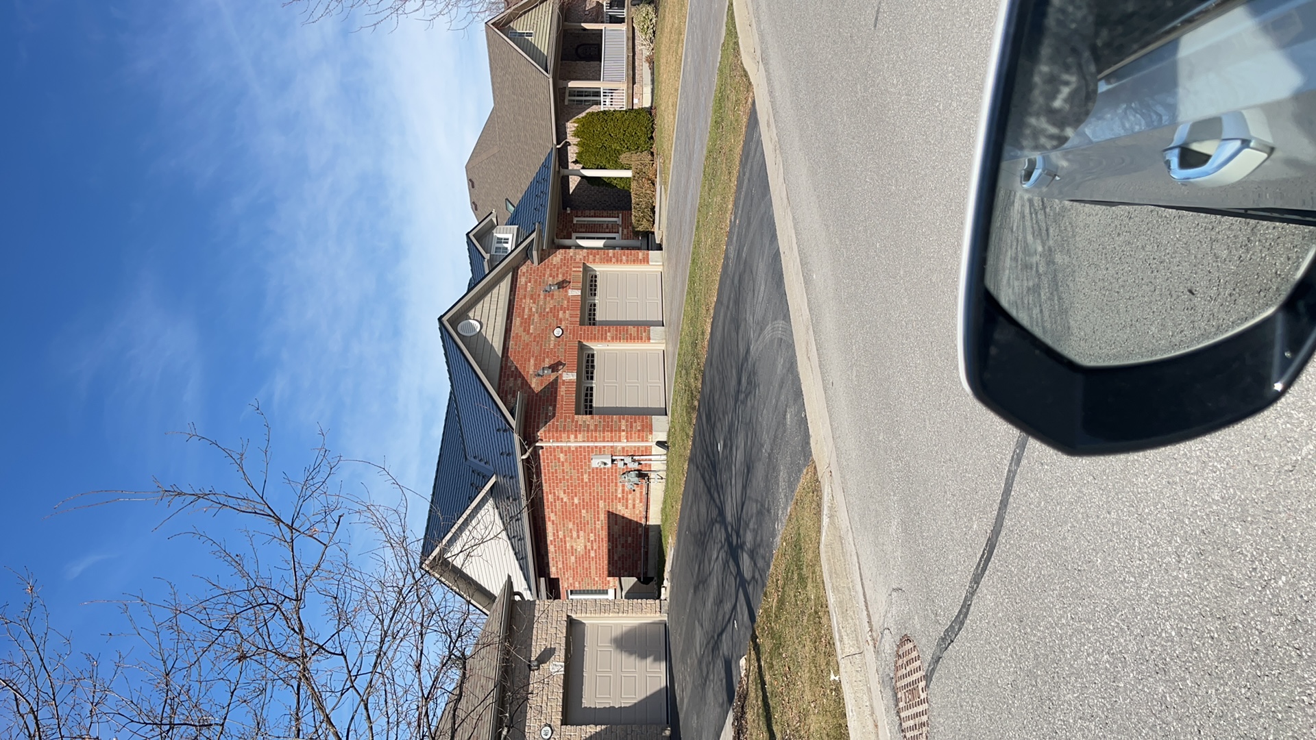 Street-view of a brick semi-detached home in Cobourg, ON featuring a black Interlock aluminum slate metal roof with multi-hip profile.