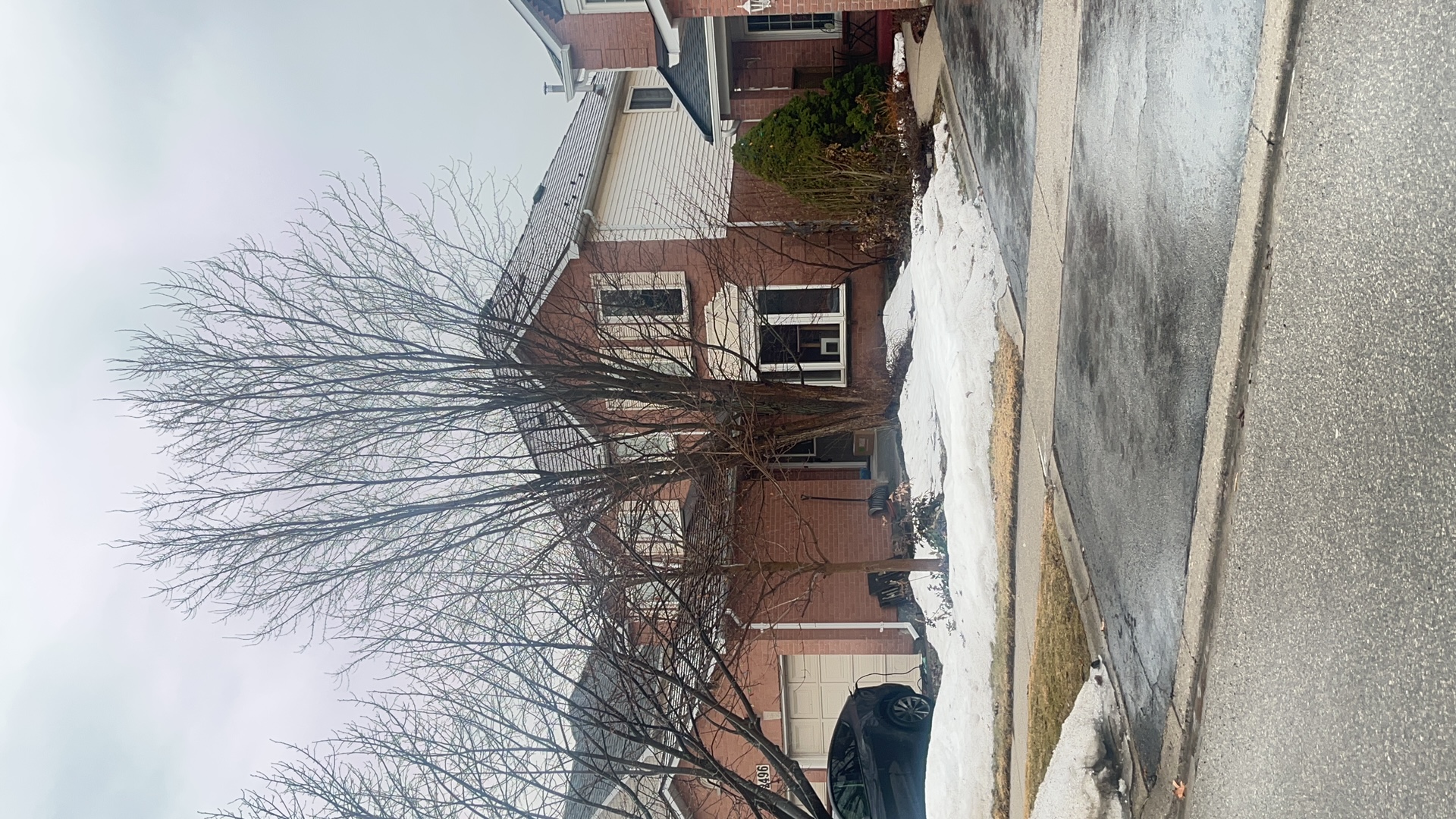 Two-storey brick Colonial home in Burlington ON with Interlock Cedar Shingle metal roof in Colonial Brown, viewed from across the street in winter.