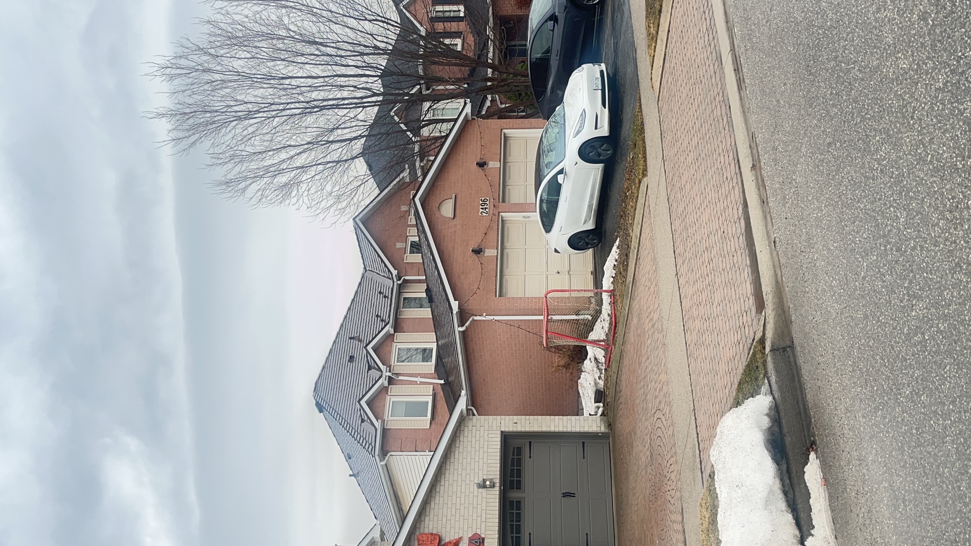 Two-storey suburban brick home in Burlington ON with Interlock Colonial Brown cedar shingle metal roof featuring multi-hip complex roofline and dormers.