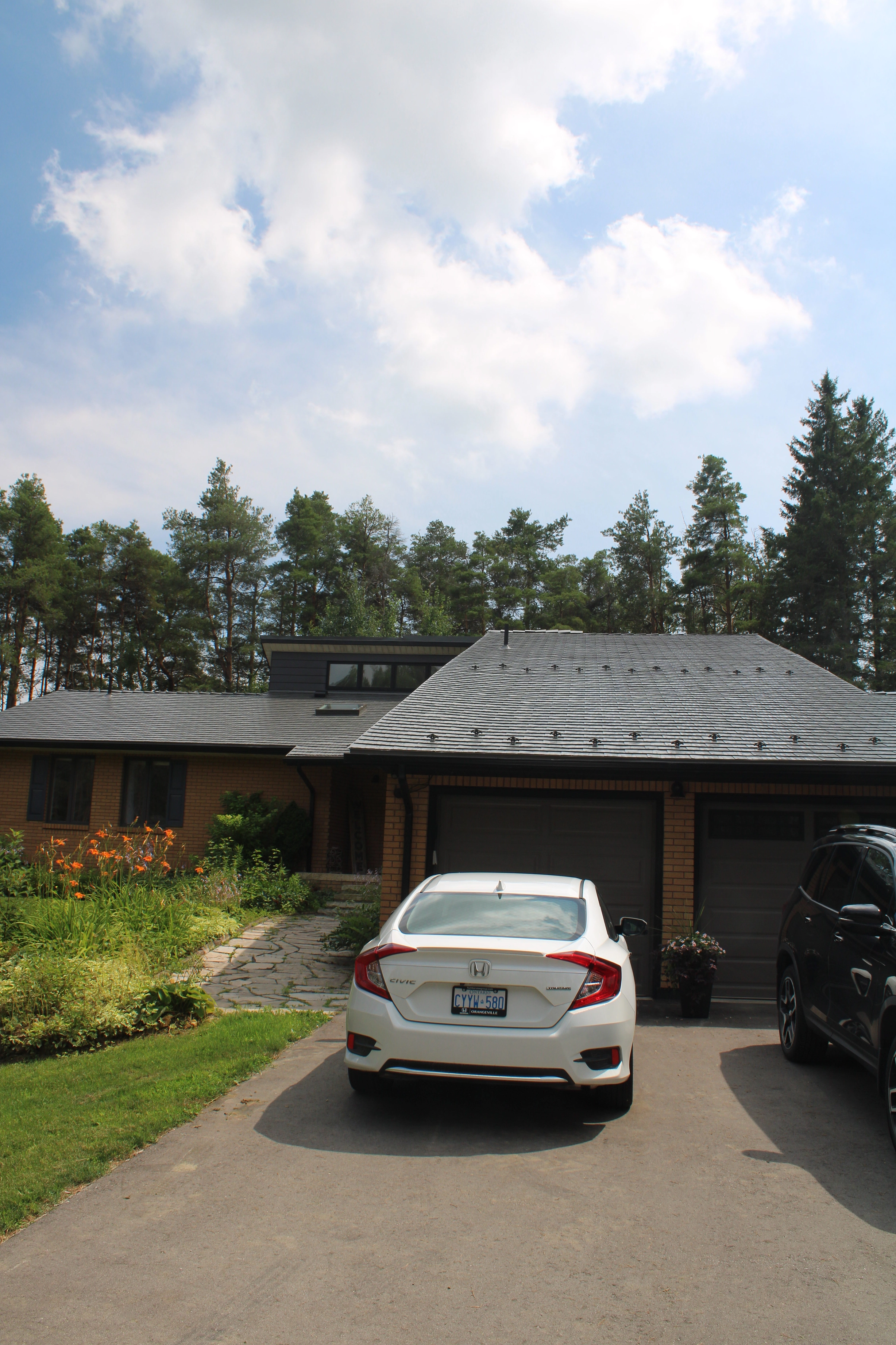 Musket Grey Interlock Cedar Shingle aluminum roof on a two-storey home with a grey roof in a forested rural area, Mono, Ontario